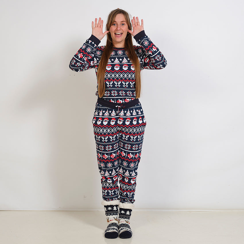 En dame poserer i et sæt julepyjamas med julemønster.