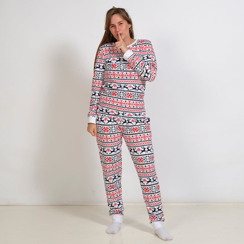 En dame i et sæt hvide julepyjamas med julemønster.