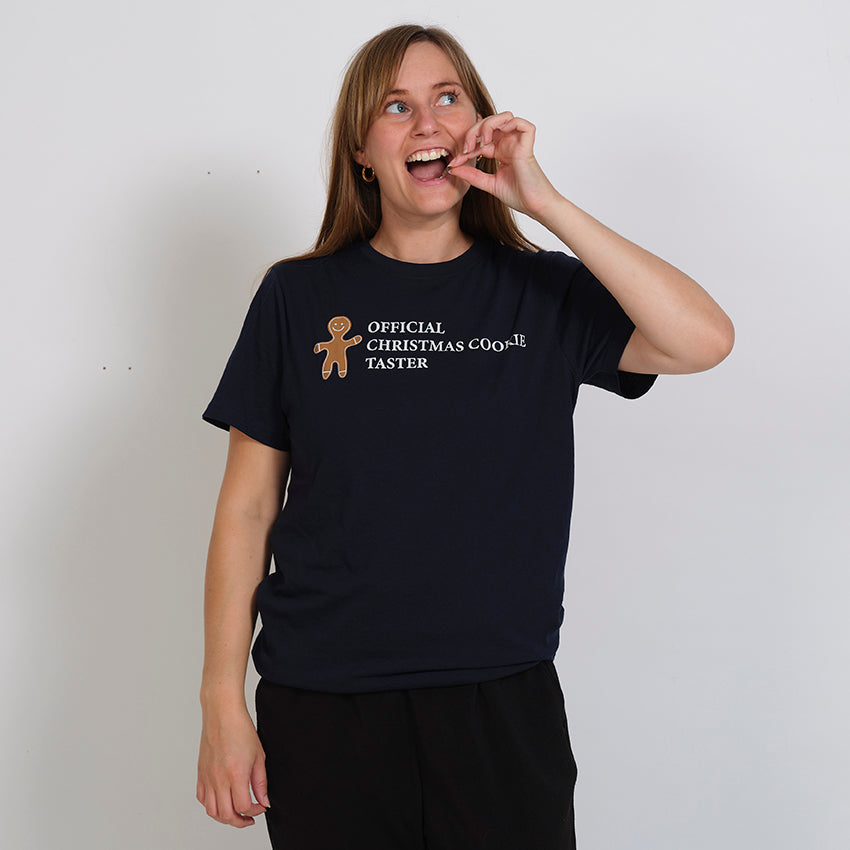 En kvinde spiser en småkage og er iført en blå T-shirt.