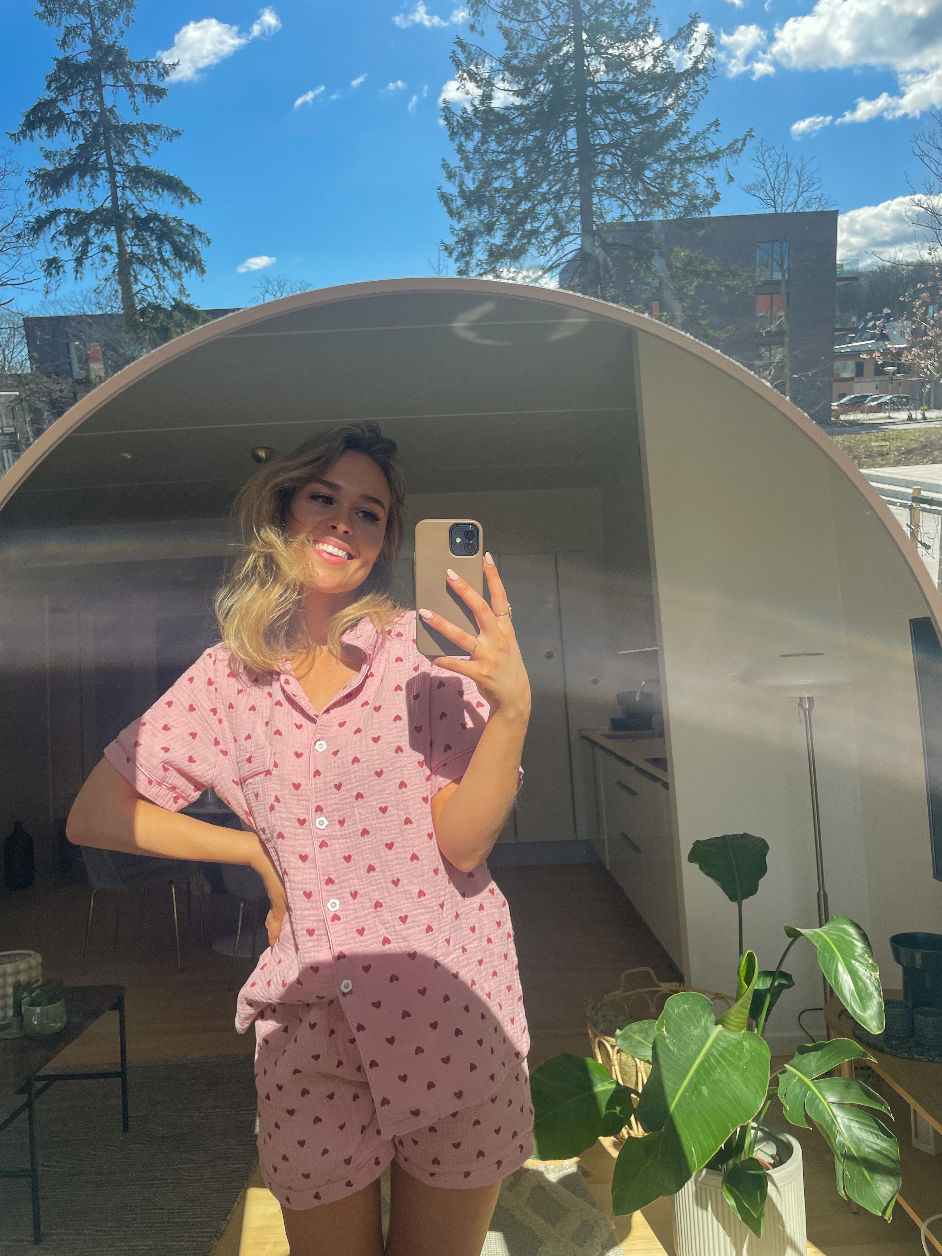 En dame poserer med et sæt rosa pyjamas på.