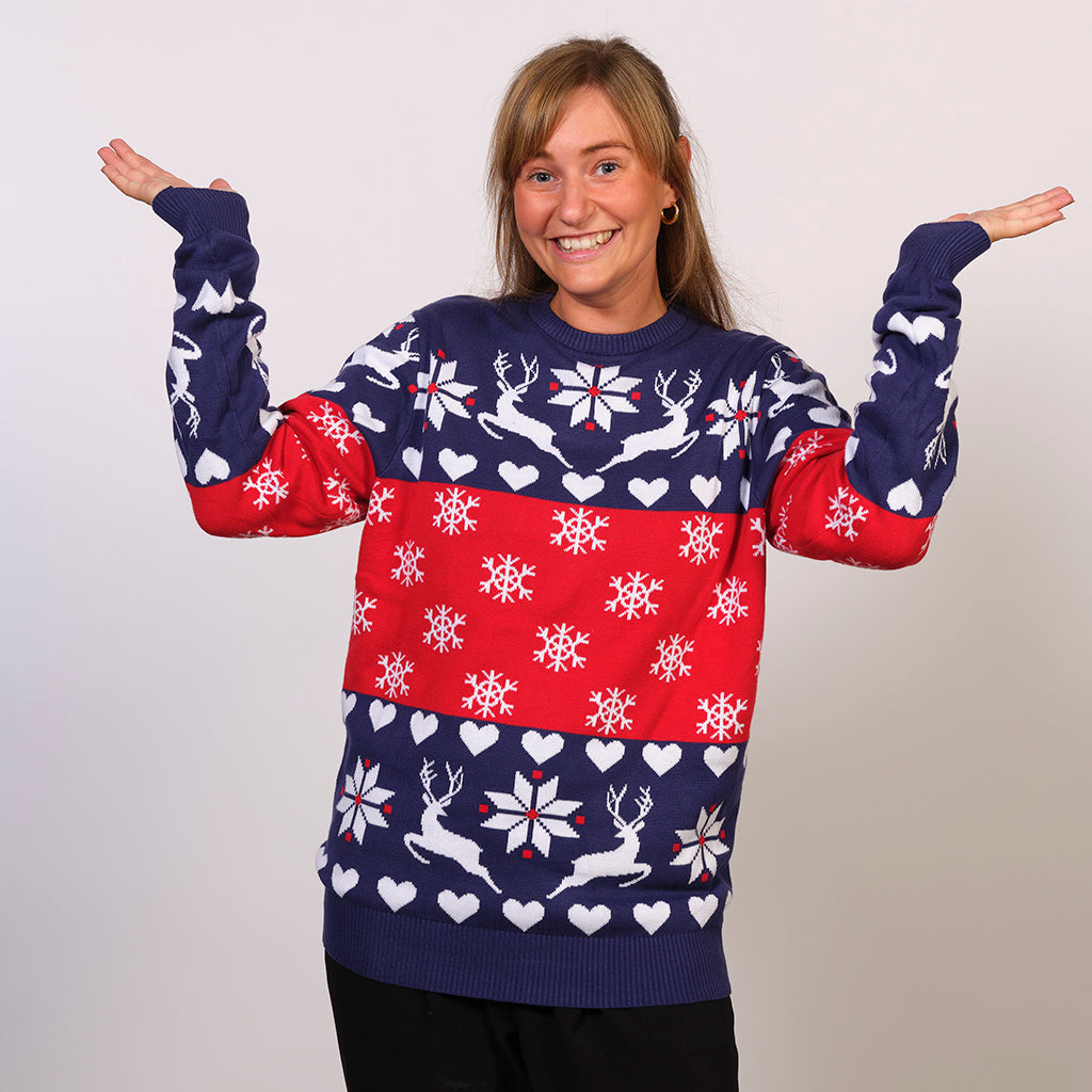 En dame poserer i en blå og rød julesweater med snefnug og rensdyr på.