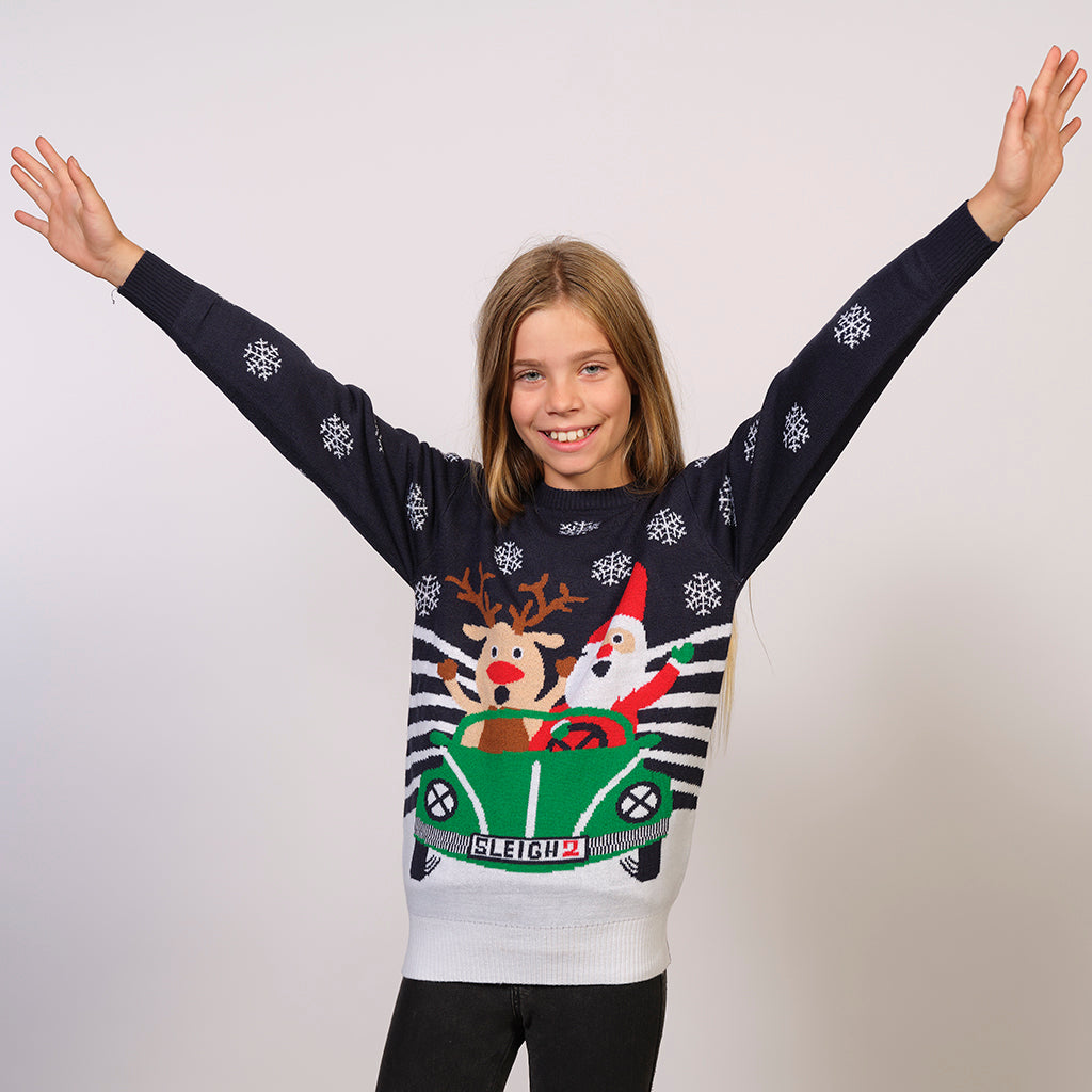 Et barn med begge hænder o vejret iført en julesweater med juleprint på.