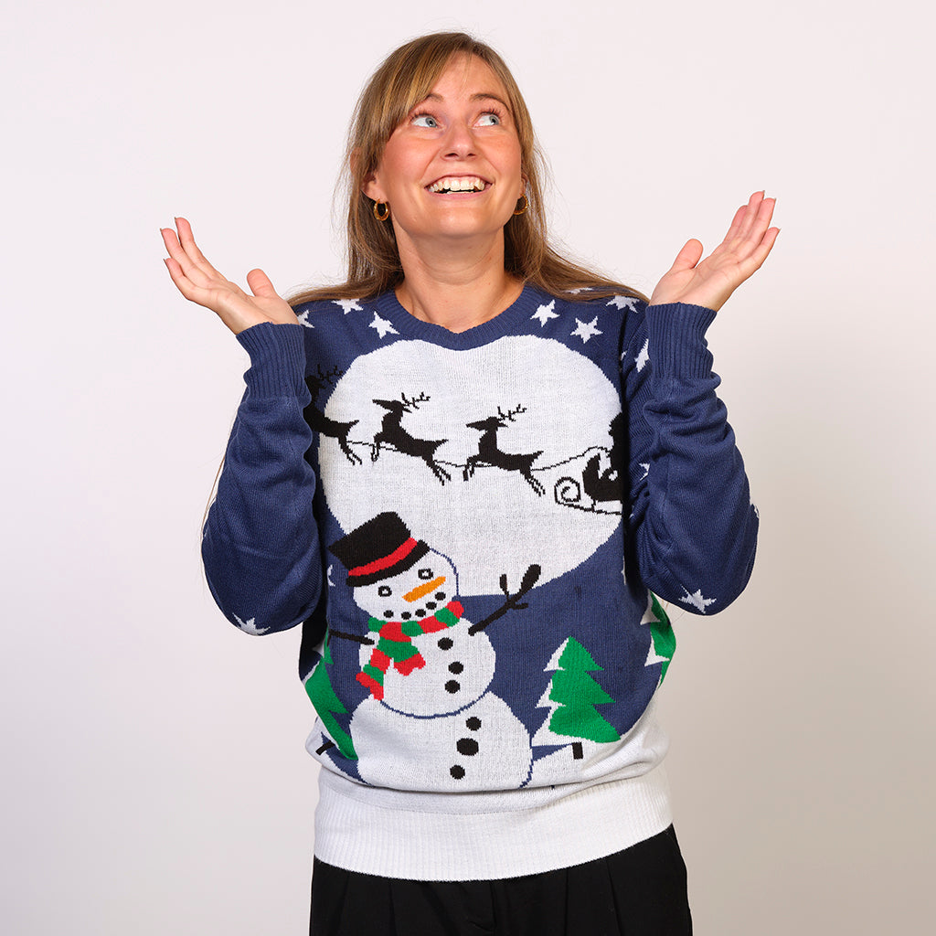 En poserende kvinde i en blå julesweater med en snemand.