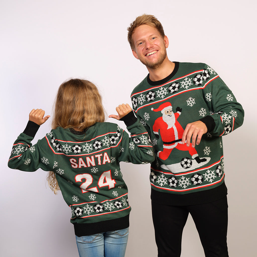 En mand og et barn iført samme grønne julesweater med fodbolde på.