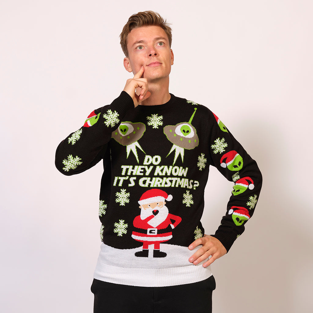 En mand iført en julesweater pyntet med en julemand, rumvæsner og ufoer.