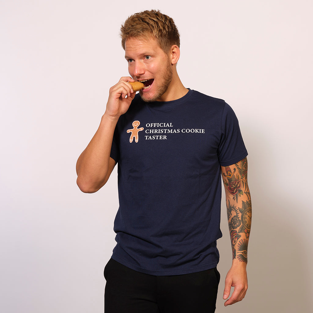 En mand spiser en honningkage og er iført en blå T-shirt med en kagemand på.