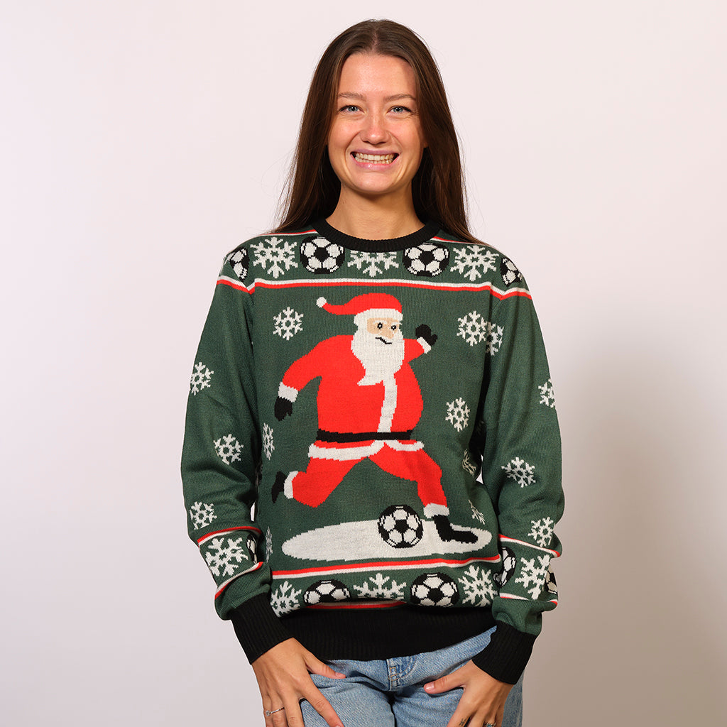 En smilende kvinde iført en grøn julesweater med julemanden og fodbolde på.