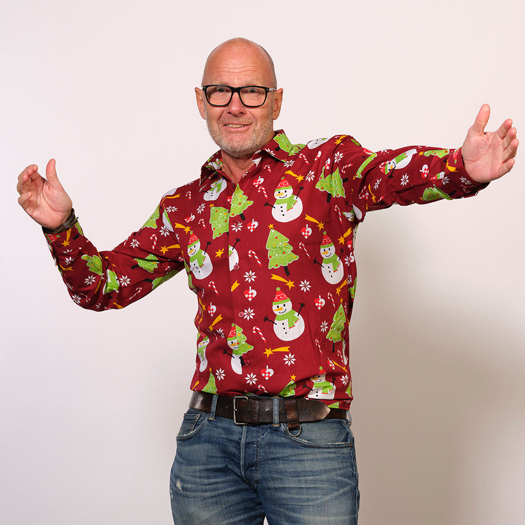 En mand med armene til siden iført en rød juleskjorte.