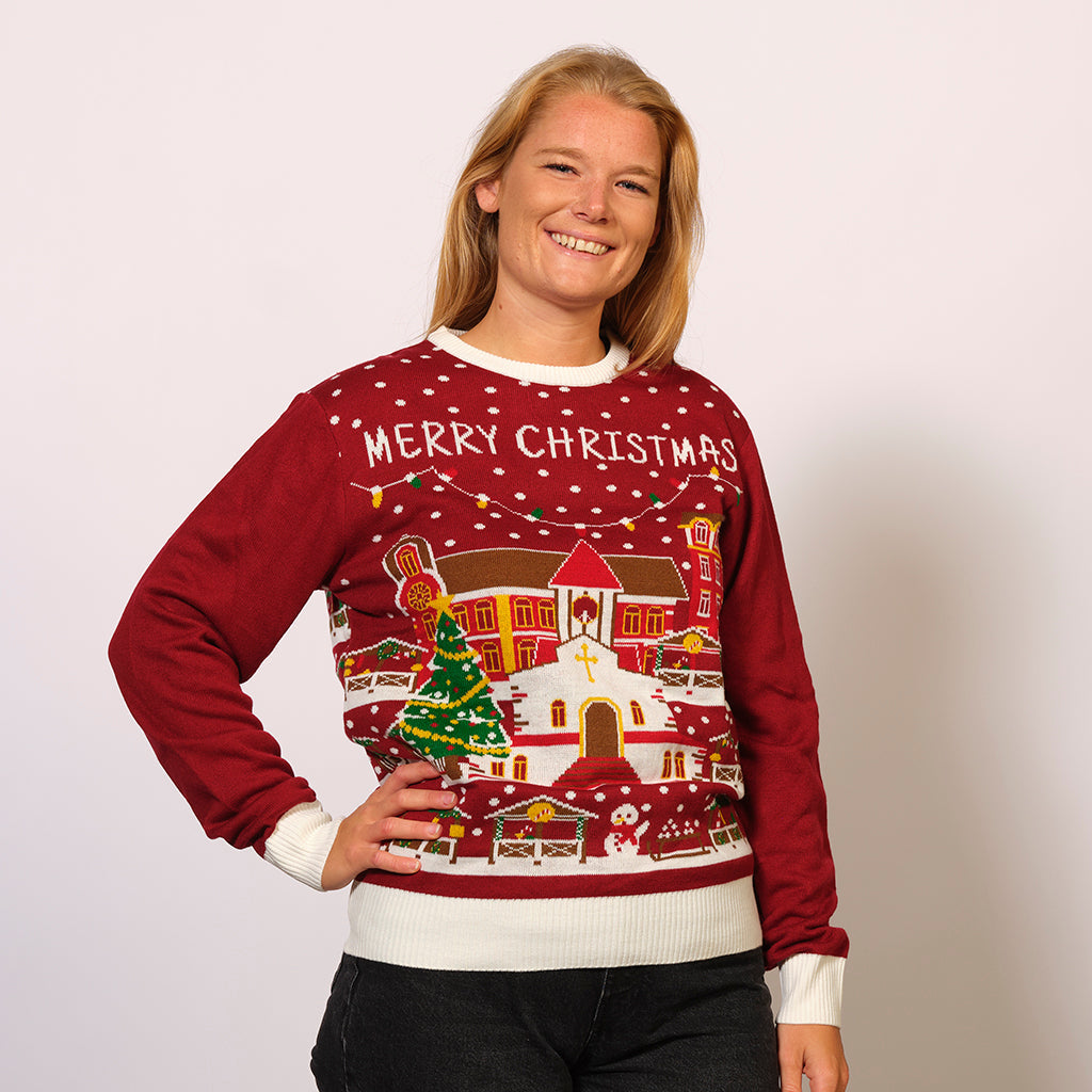 En dame poserer i en rød julesweater med en juleby på.