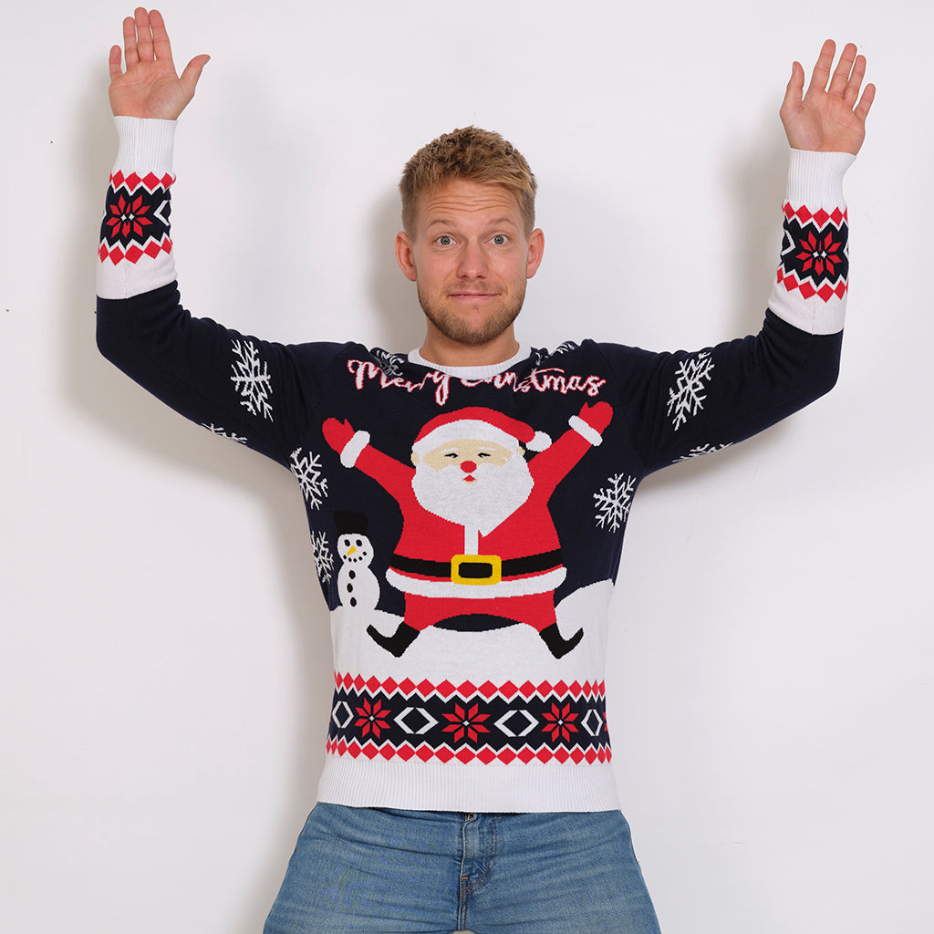 En mand med hænderne i vejret iført en julesweater med snefnug.