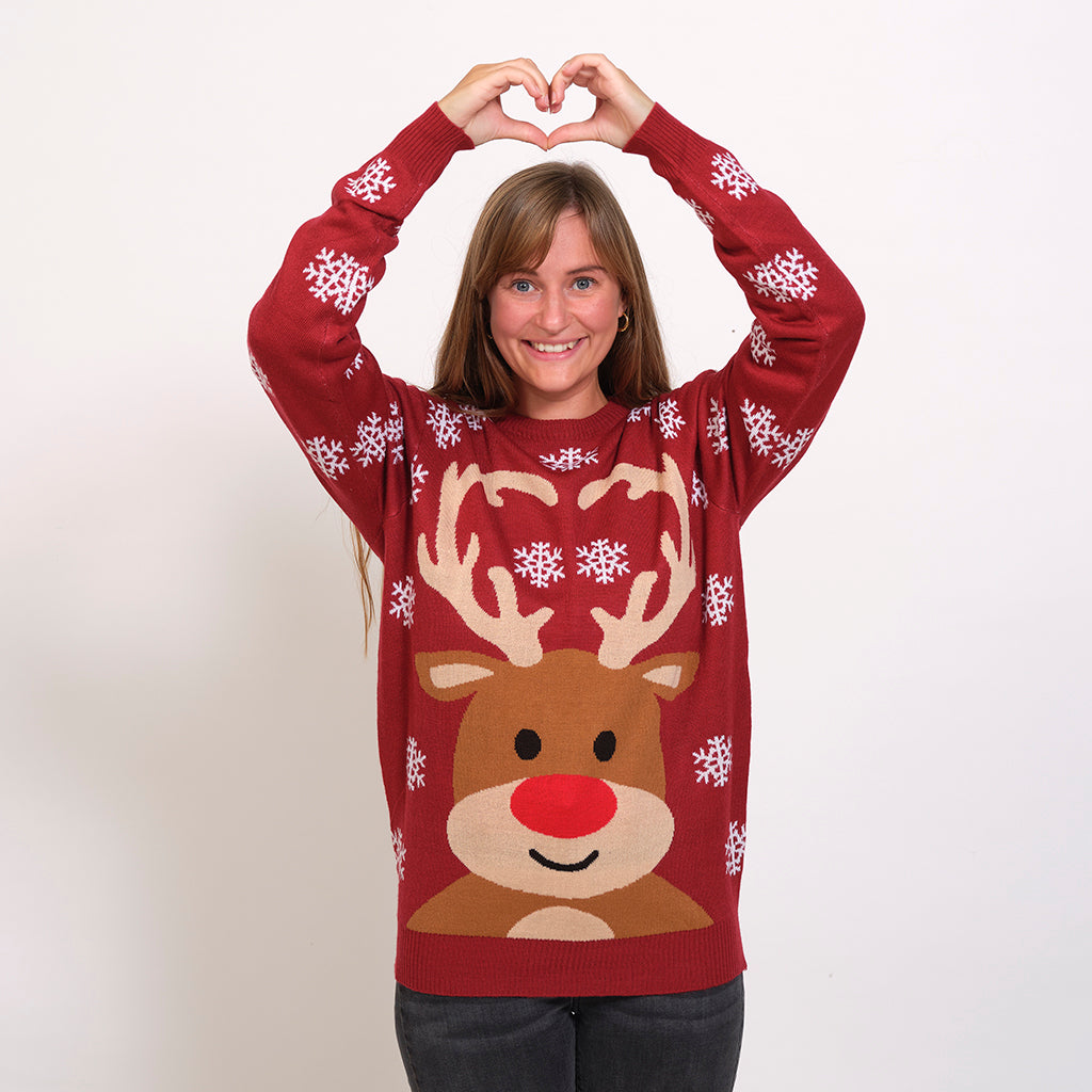En smilende dame poserer i en rød julesweater med et rensdyr på.