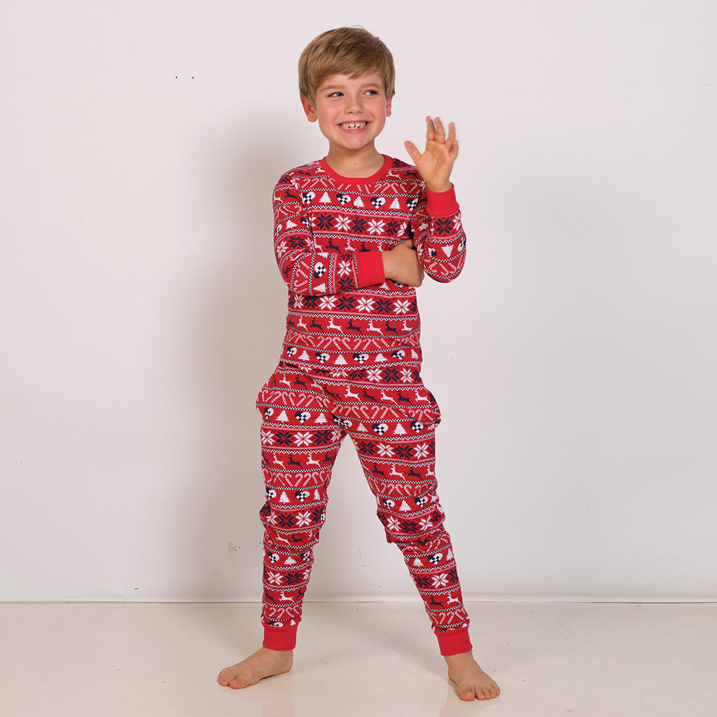 Et barn poserer i sinde røde julepyjamas.