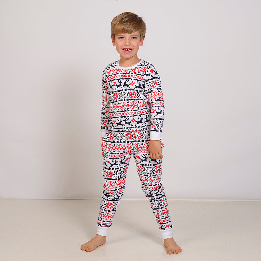 Et barn med julepyjamas med rensdyr og julemønster.