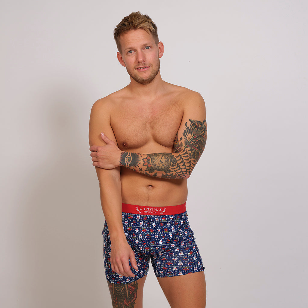 En mand poserer i blå juleunderbukser.