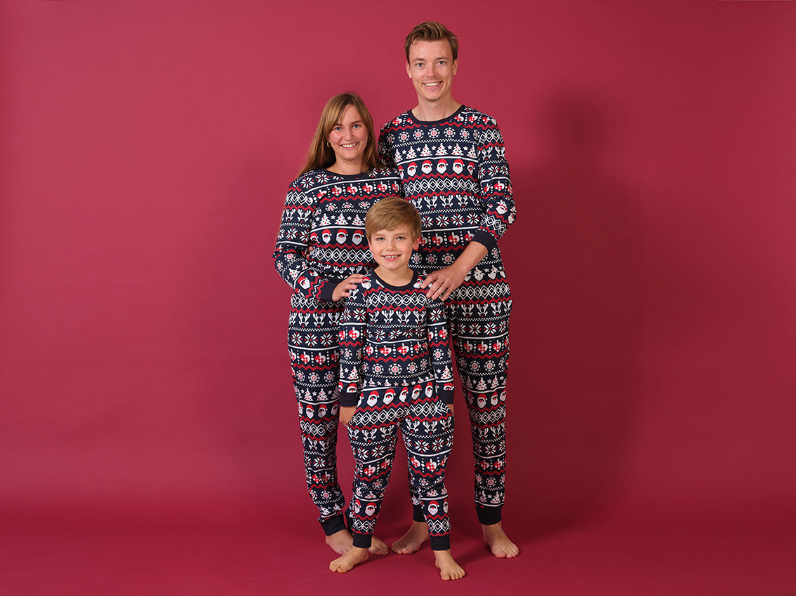 En mand, en kvinde og et barn iført hver deres sæt blå julepyjamas.