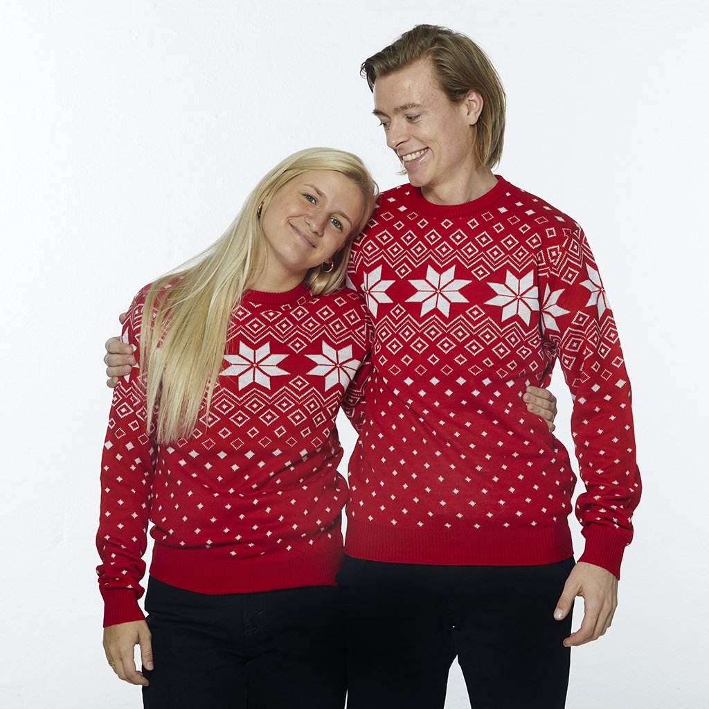 En dame og en mand hver iført en rød julesweater med julemønster.