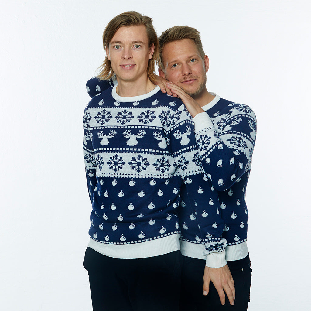 To mænd poserer sammen i en julesweater med rensdyr, julekugler og snefnug.