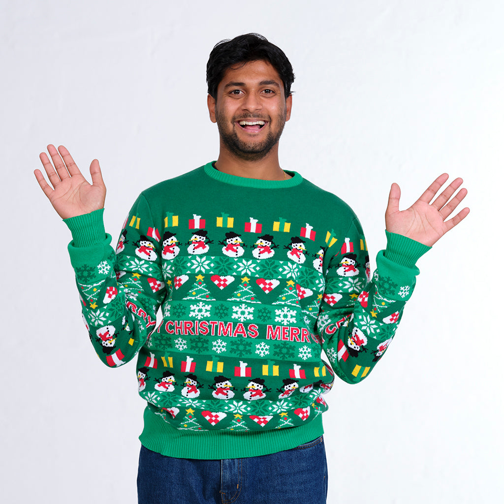 En mand poserer med begge hænder i vejret i en grøn julesweater.