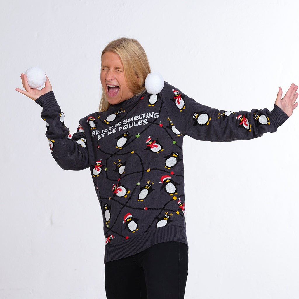 En dame med snebolde i hænderne er iført en julesweater.