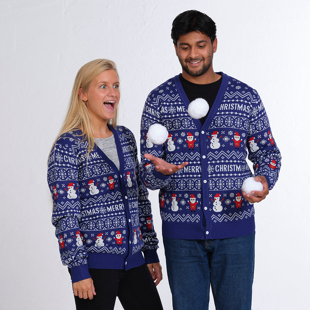 En mand og en dame kaster snebolde op i luften og poserer iført en blå julecardigan.