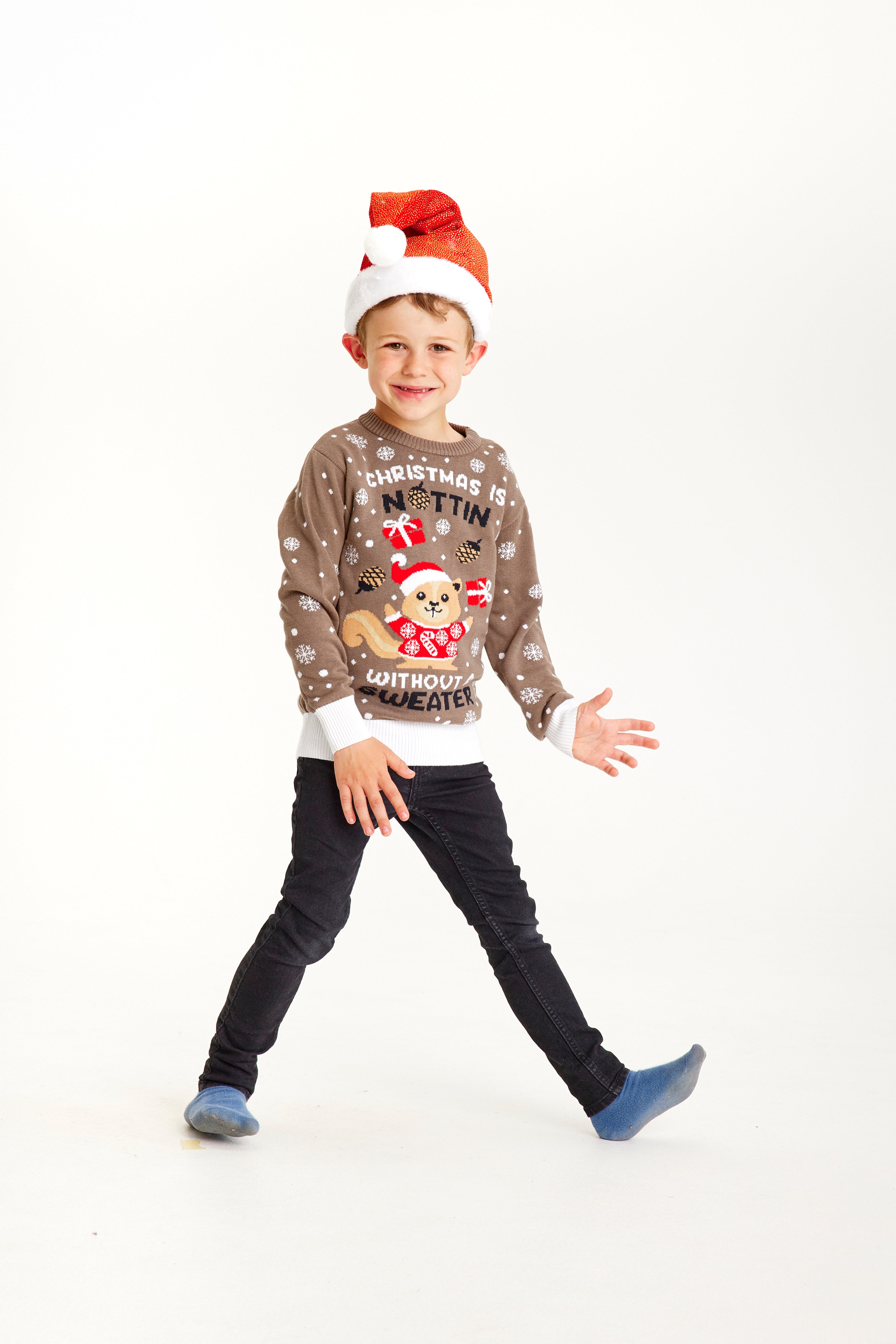 En smilende dreng iført en julesweater med et juleegern med nissehue og snefnug omkring sig.