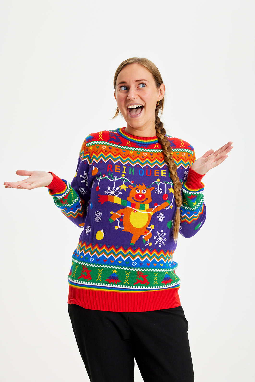 En smilende iført en julesweater med alle regnbuens farver.
