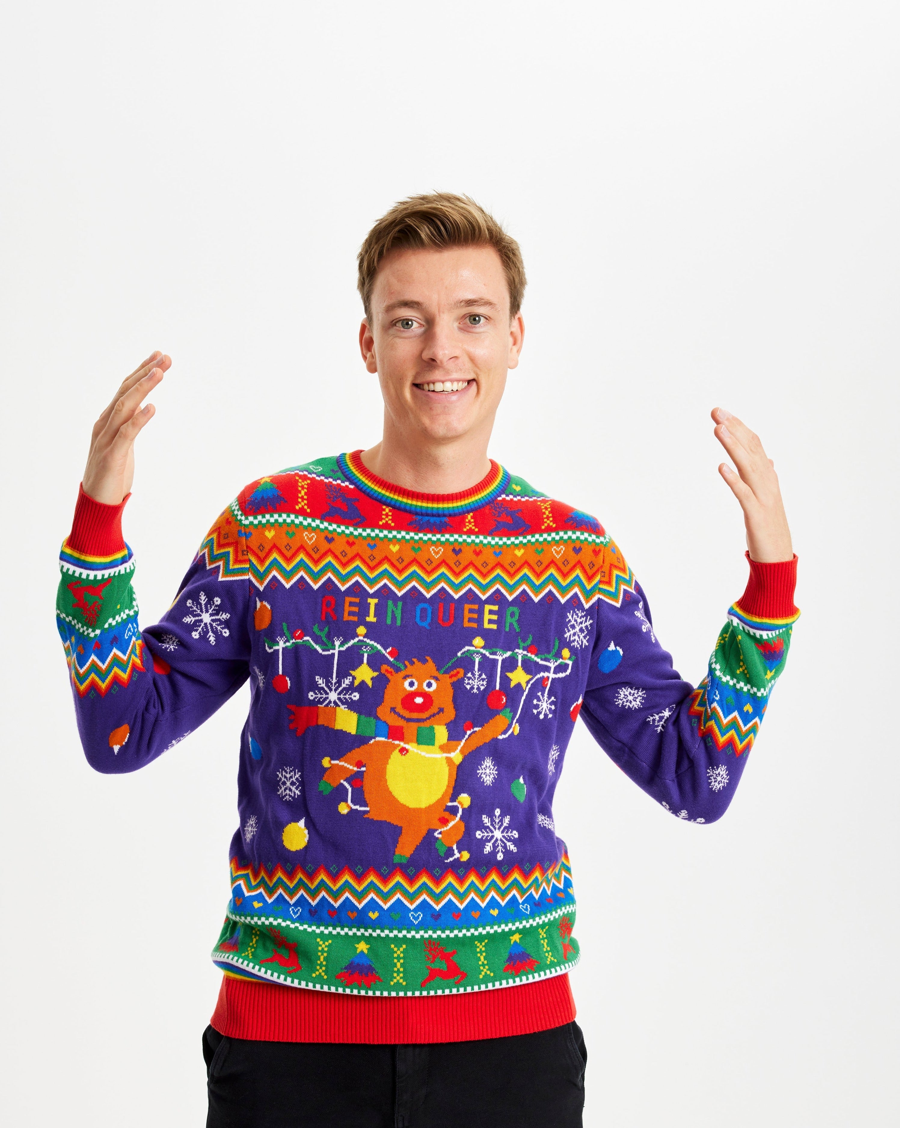 En smilende mand poserer i sin farverige julesweater.