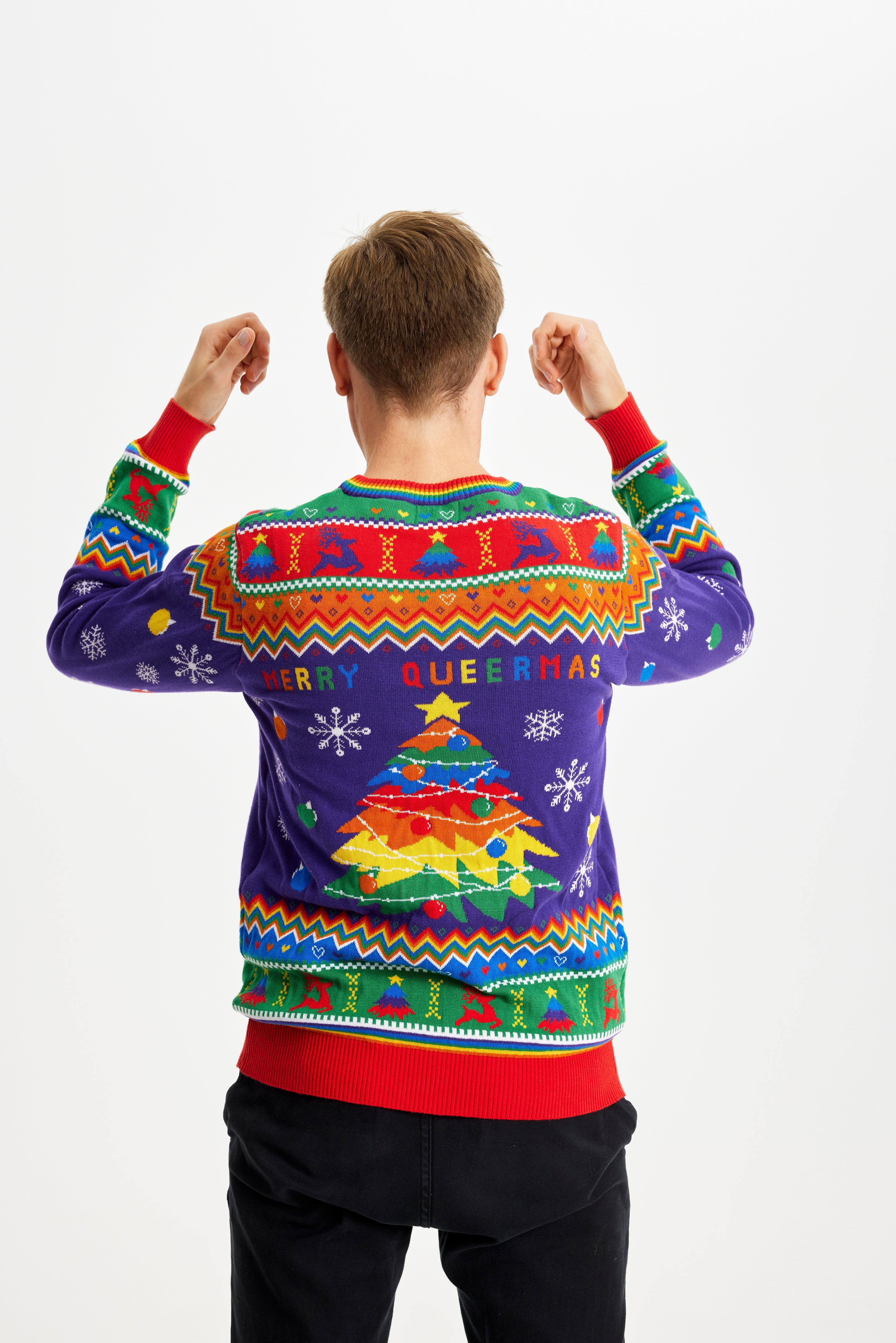 En mand med ryggen tli står i en julesweater.