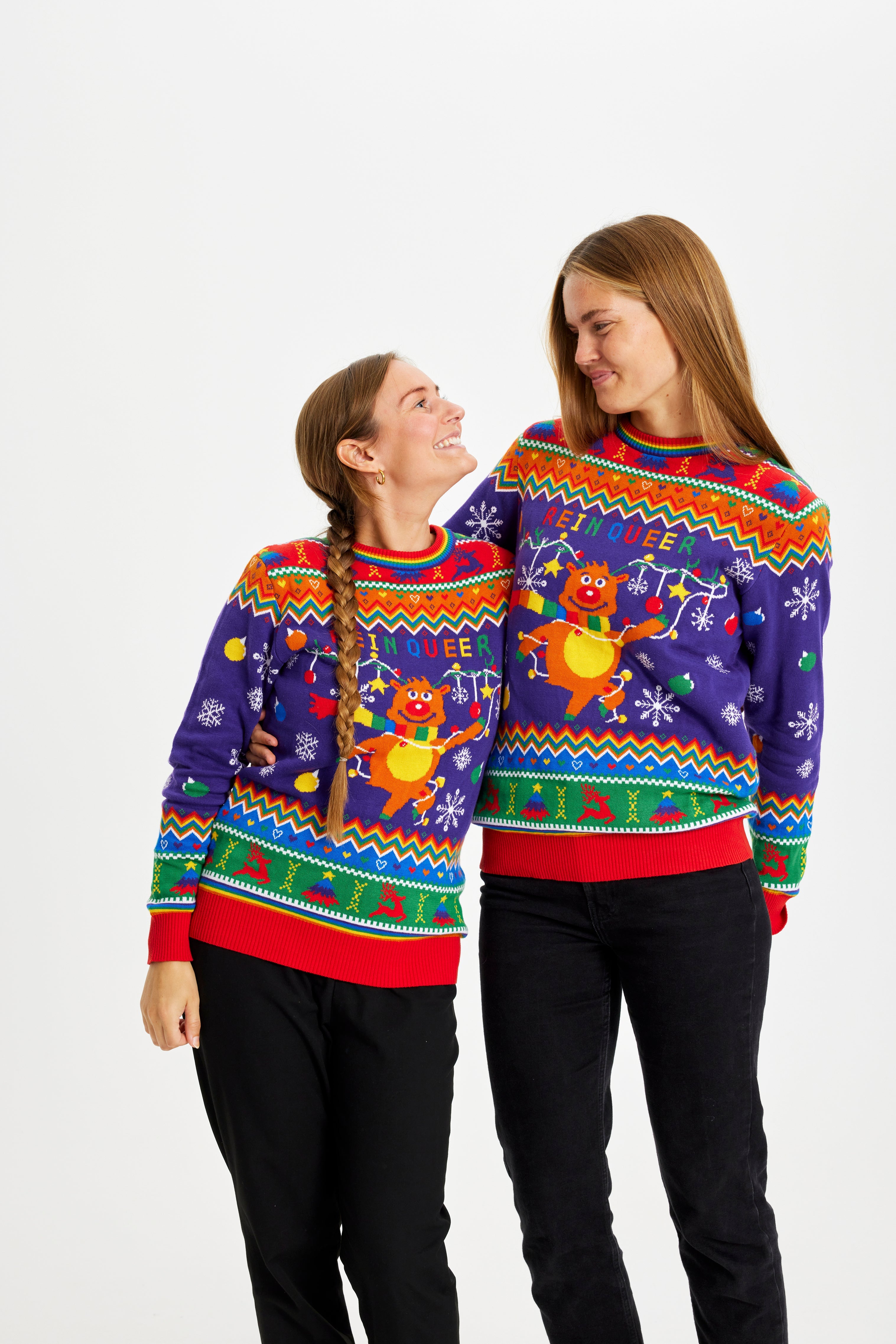 Et par iført farverige julesweatre med et rensdyr på.