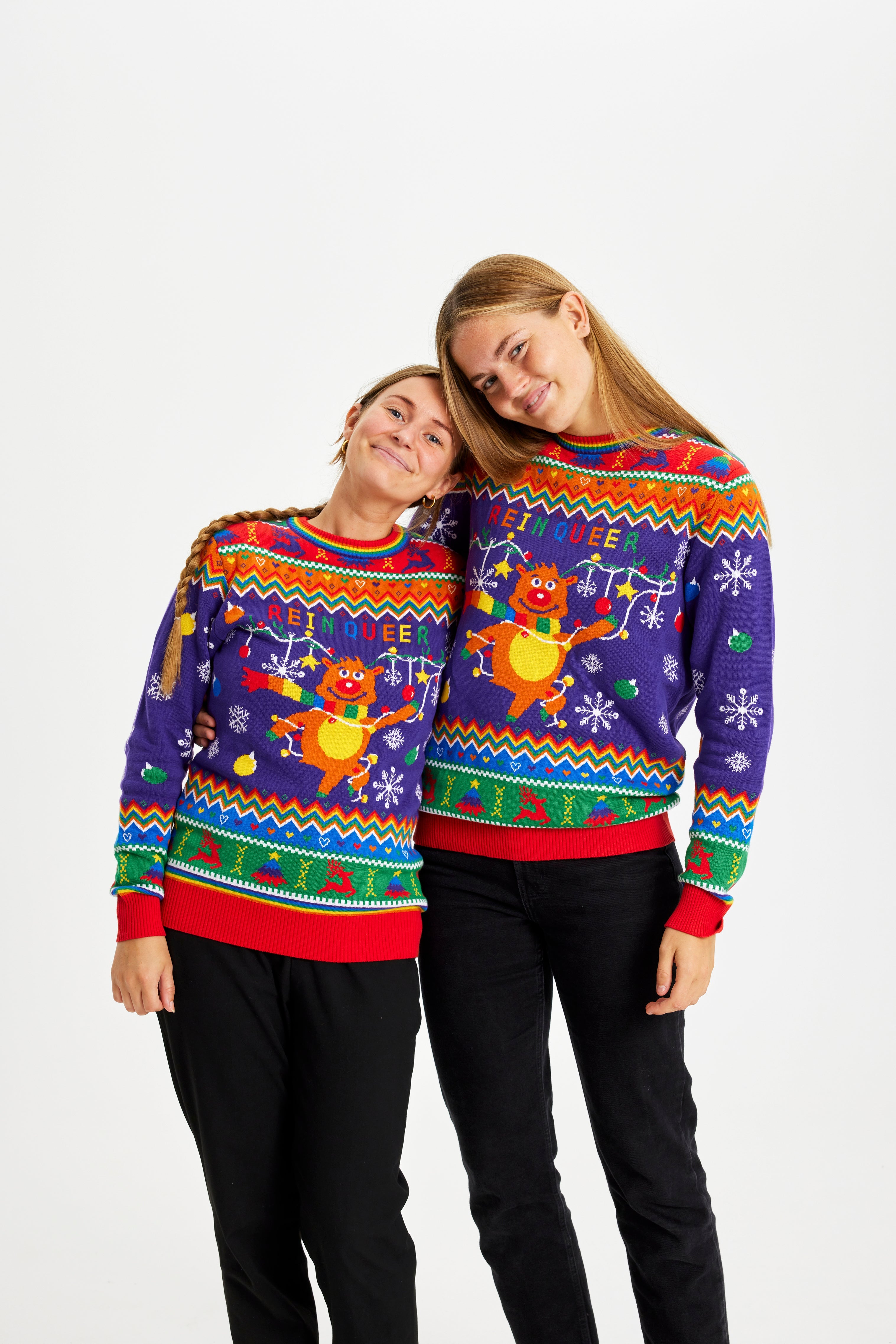 To kvinder iført hver deres julesweater med mønster og et rensdyr på.