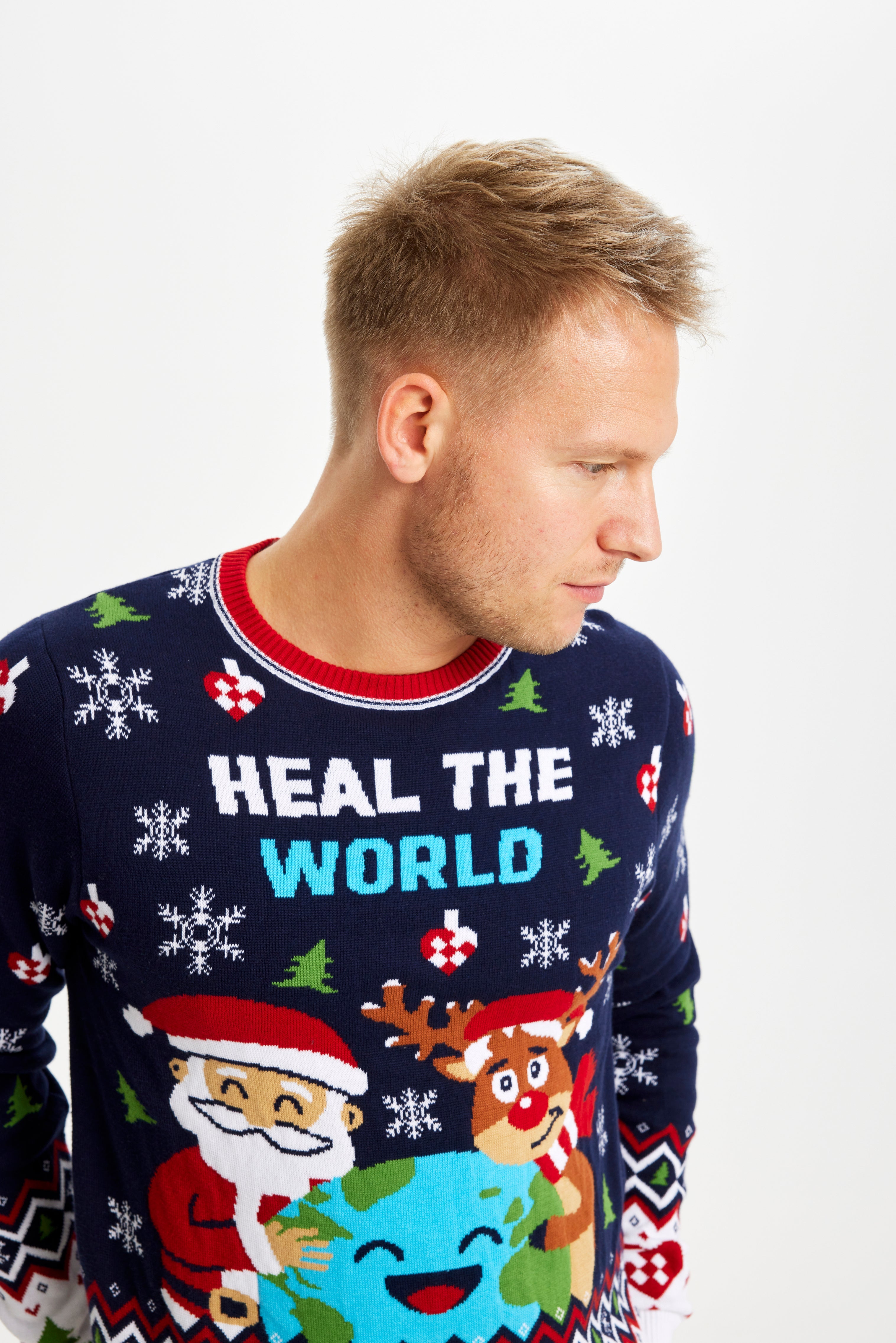 En mand kigger til siden og er iført en blå julesweater med en planet på.
