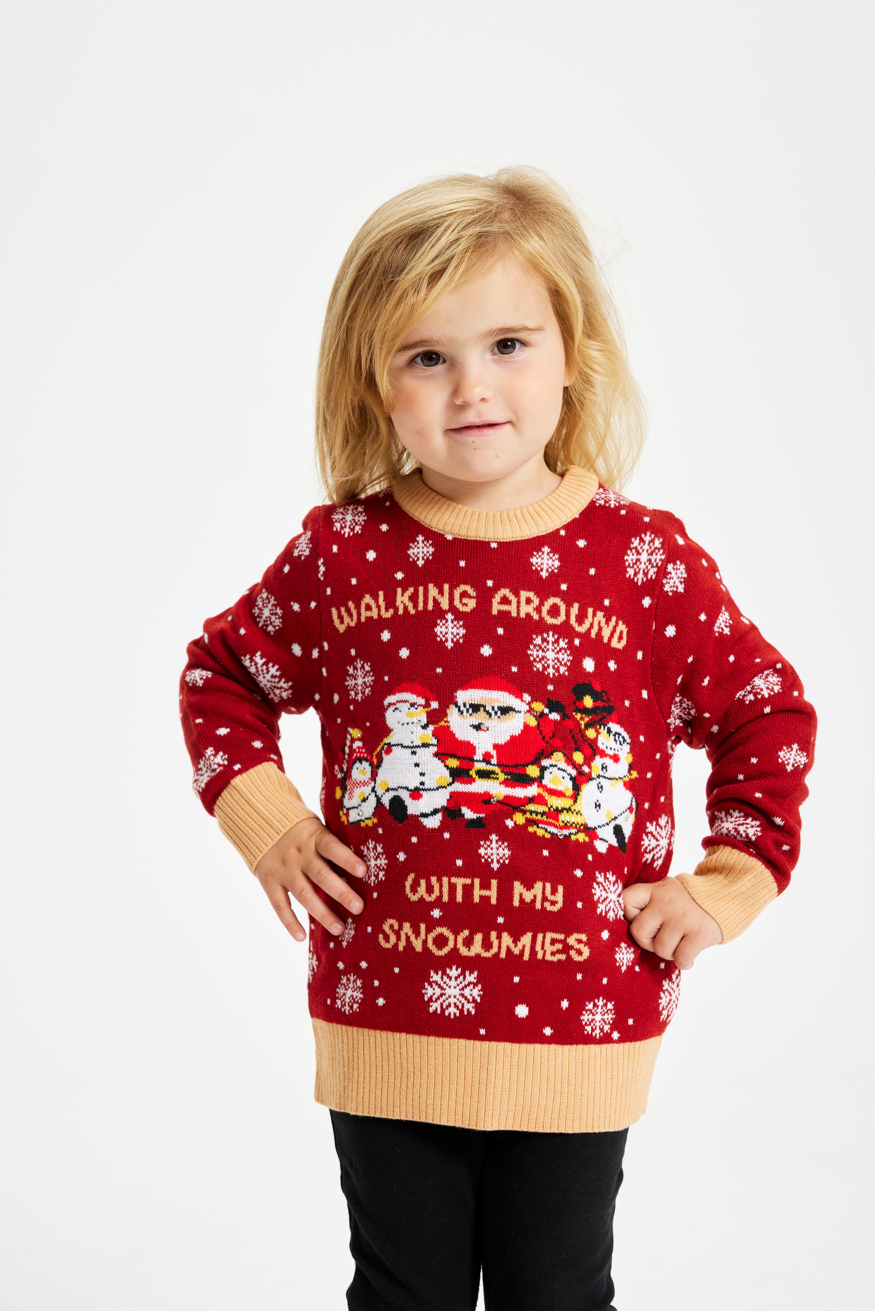 Et barn med hænderne i siden iført en rød julesweater.