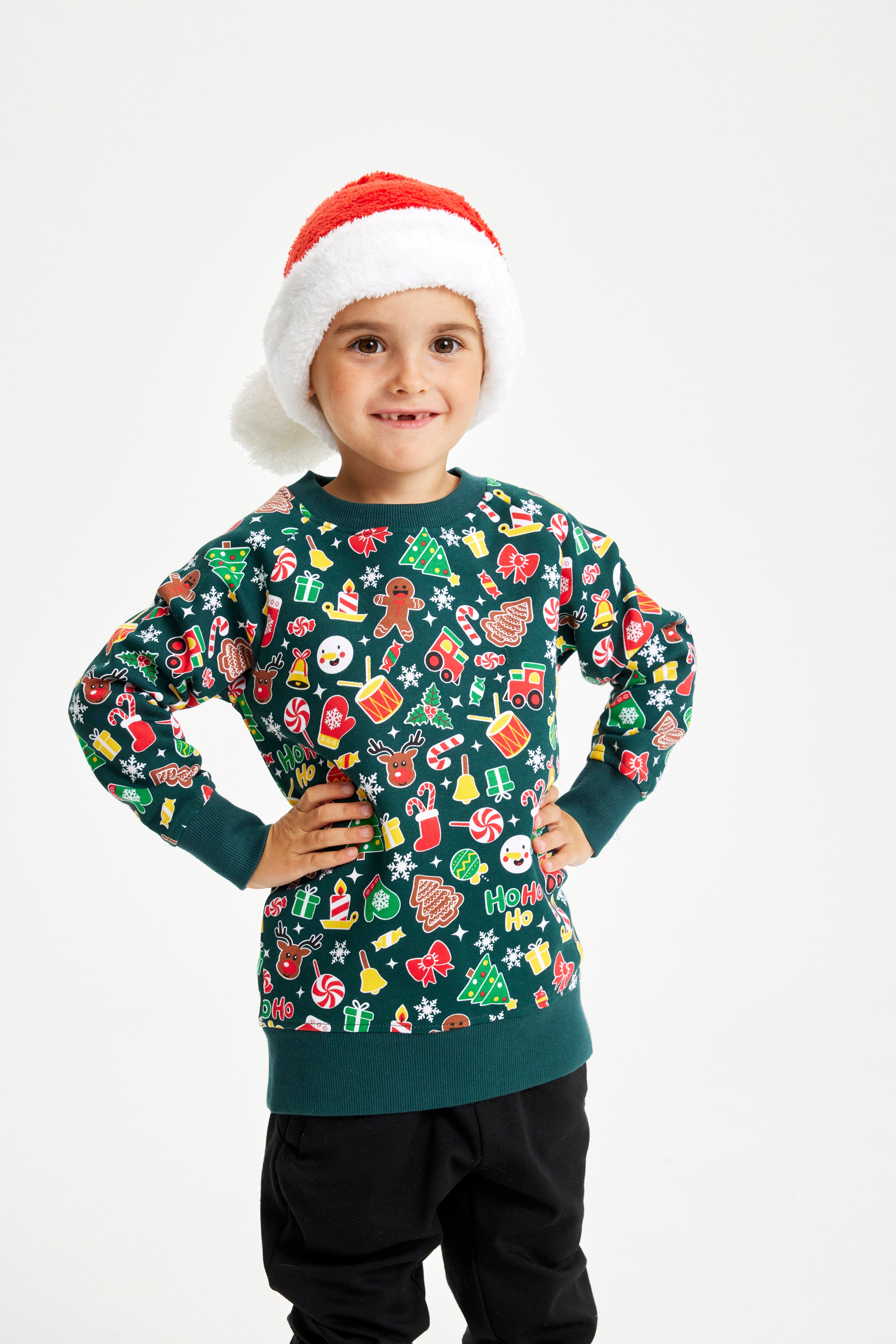 Et barn med en nissehue og en grøn julesweater.