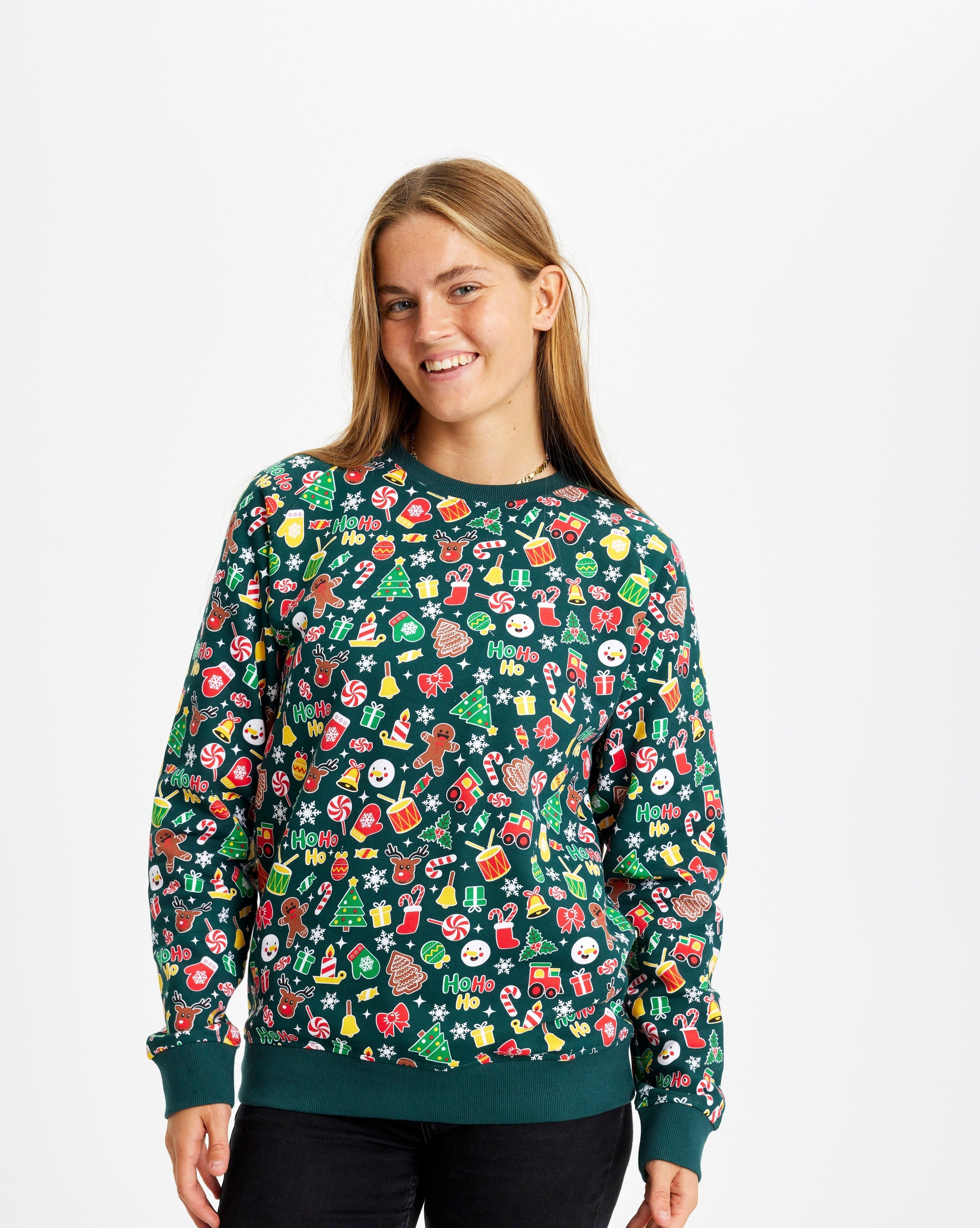 En smilende kvinde iført en grøn julesweater med julemønster.