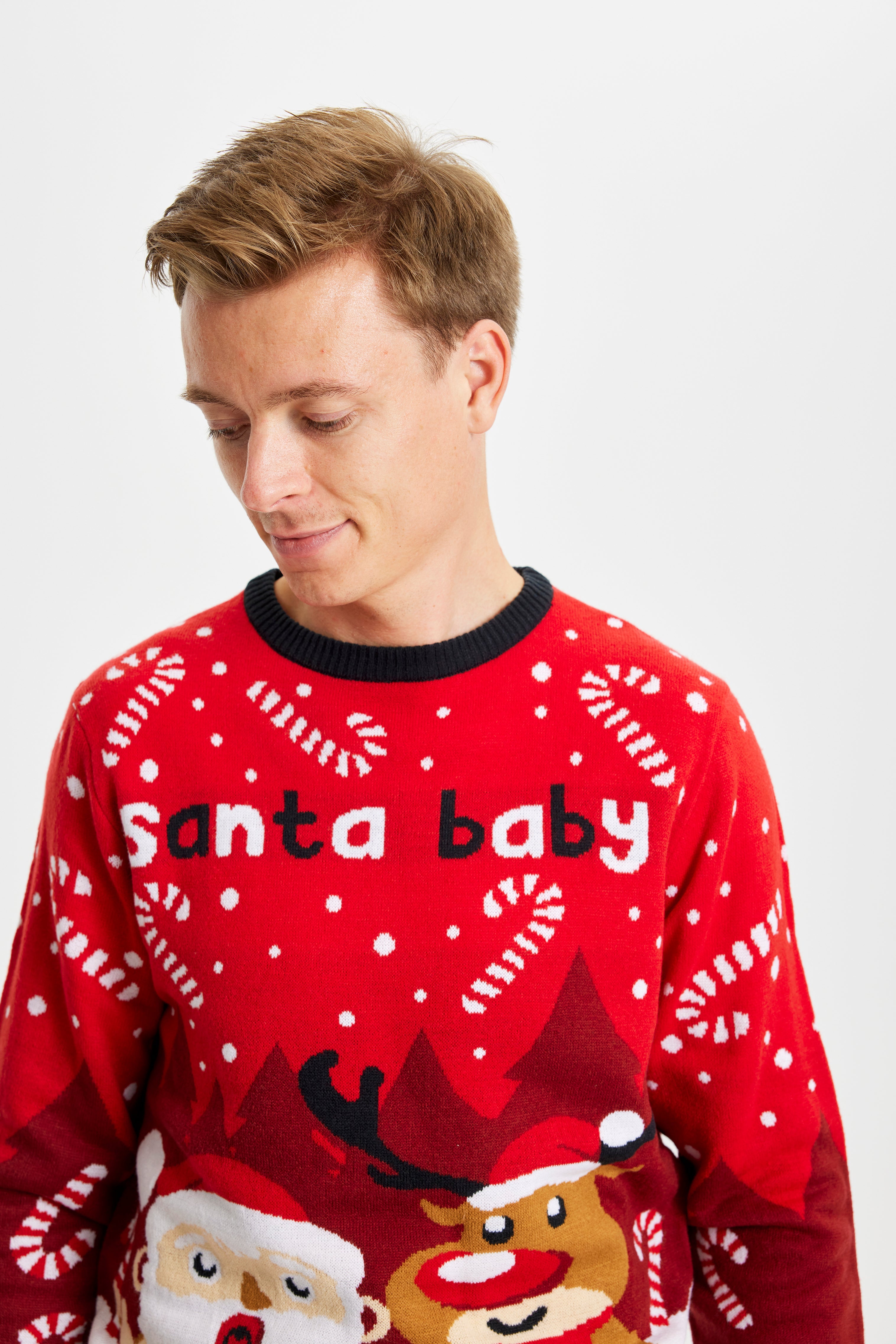 En mand kigger ned og er iført en rød julesweater med citatet 