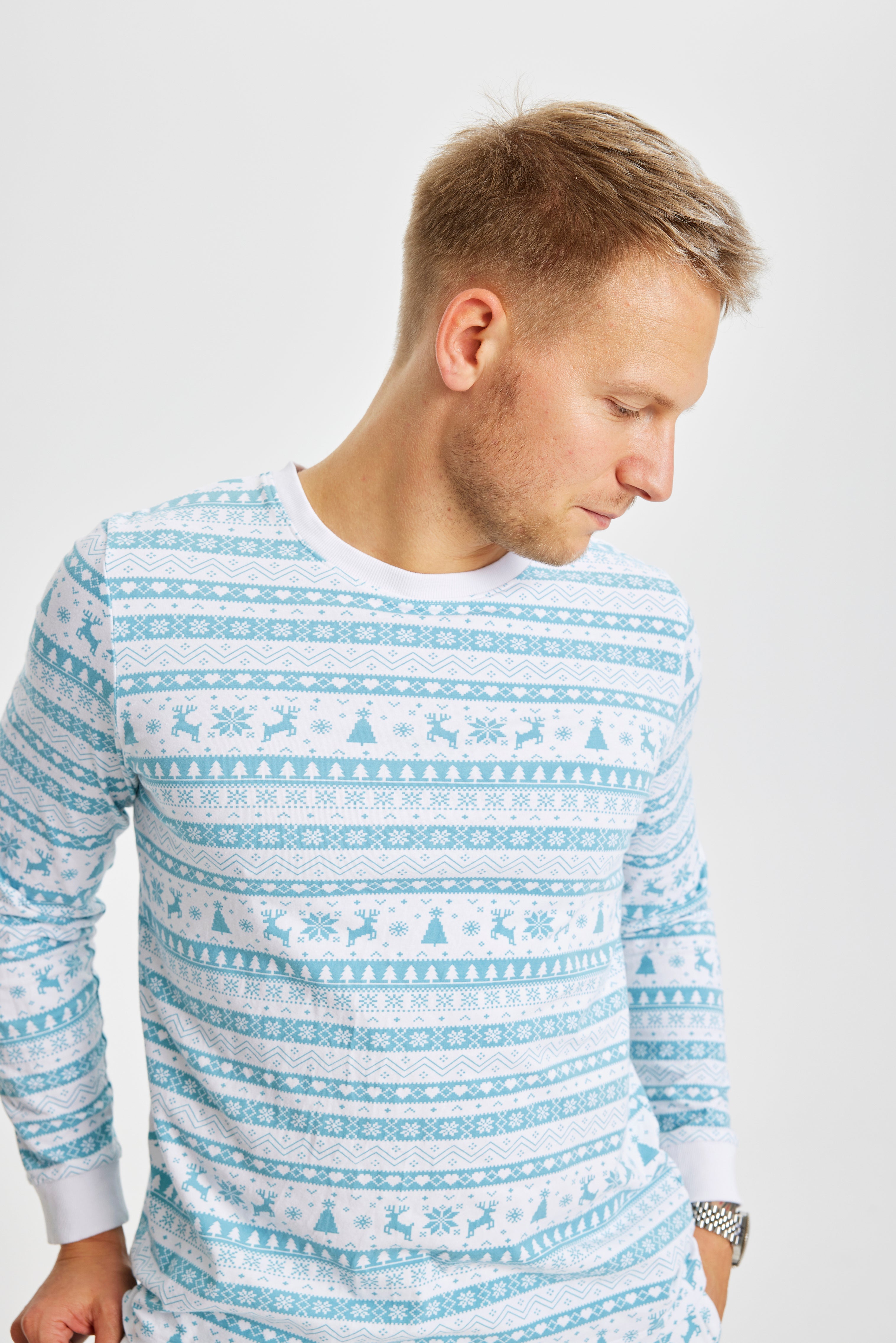 En mand, der kigger ned er iført en pyjamas med juletema, hvor der er rensdyr og juletræer på.