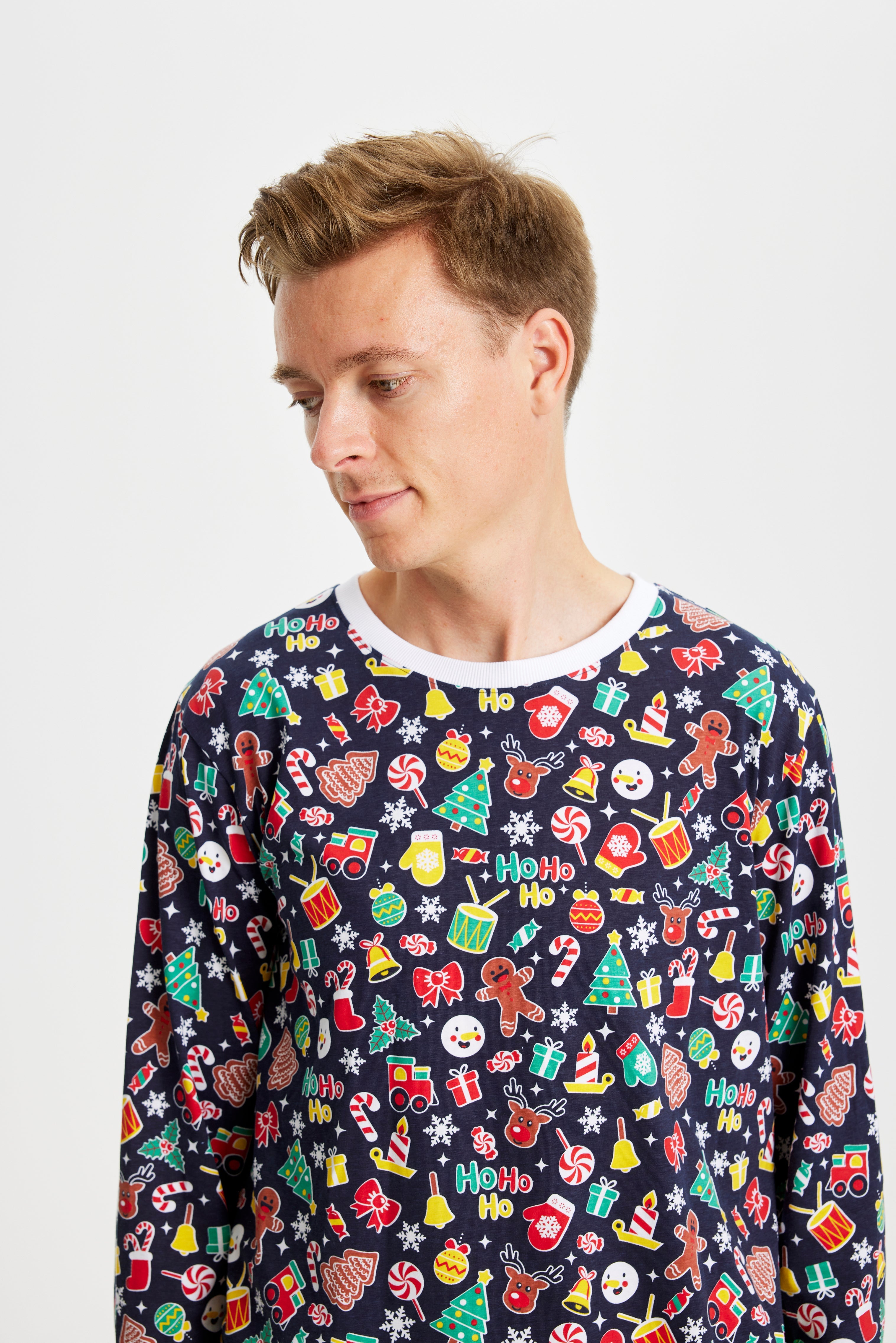 En mand kigger nedad og er iført en pyjamas med juletema med juletræer, juleslik og trommer.