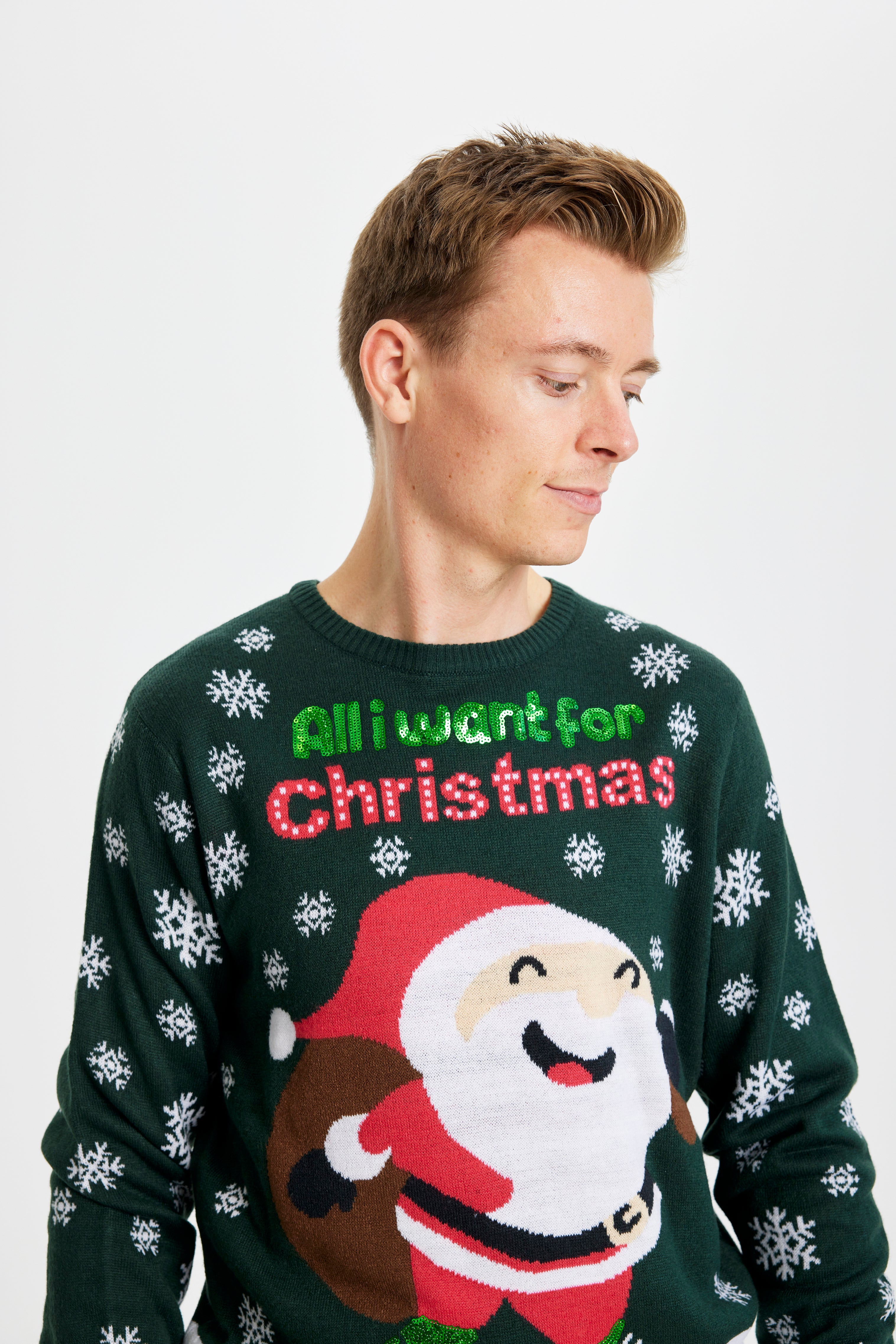 Et billede af en mand fra torsoen og op, som er iført en julesweater med en munter julemand, der bærer på en gavesæk.