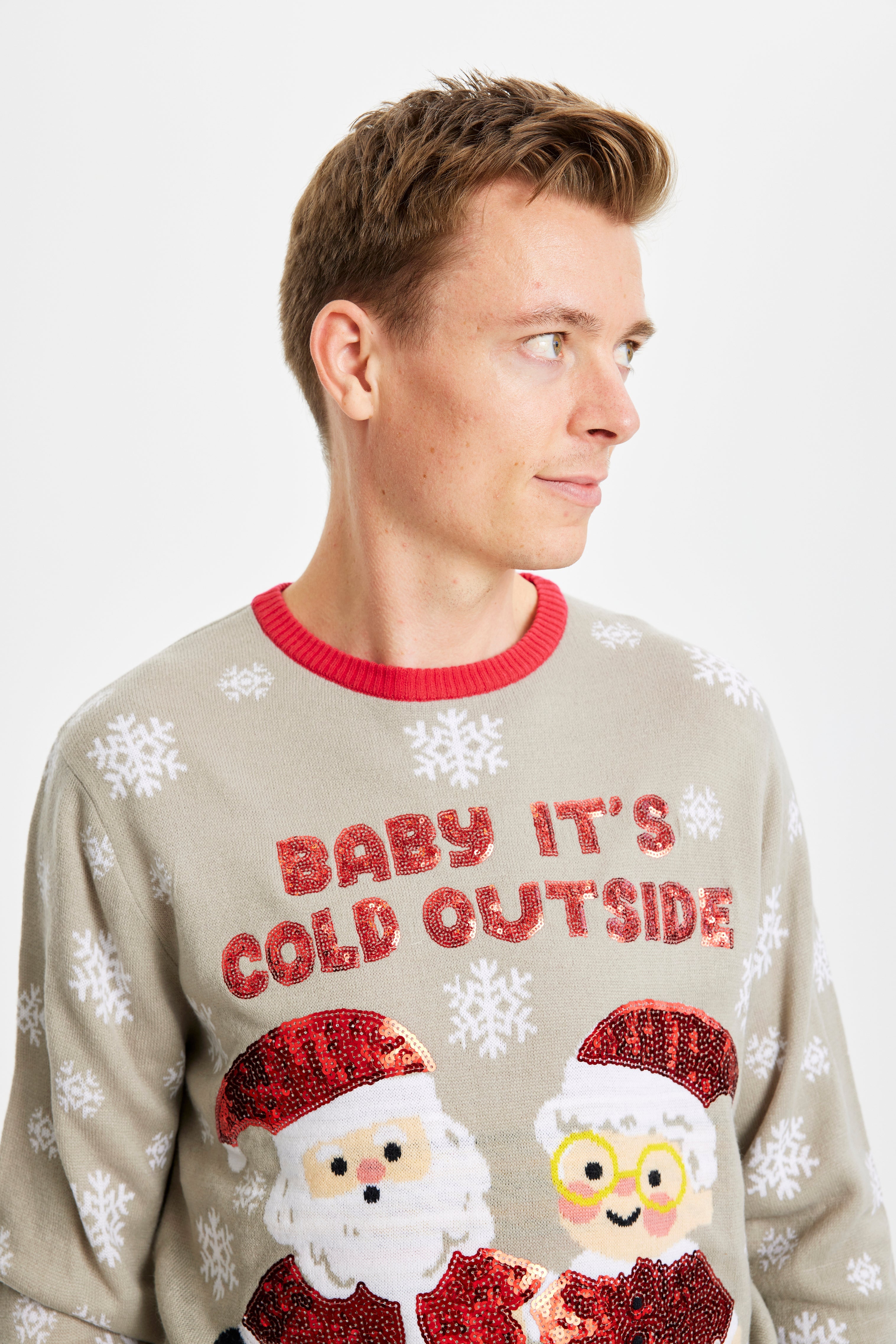 Et billede af en mand, der kigger til siden, som er iført en grå julesweater med citatet 