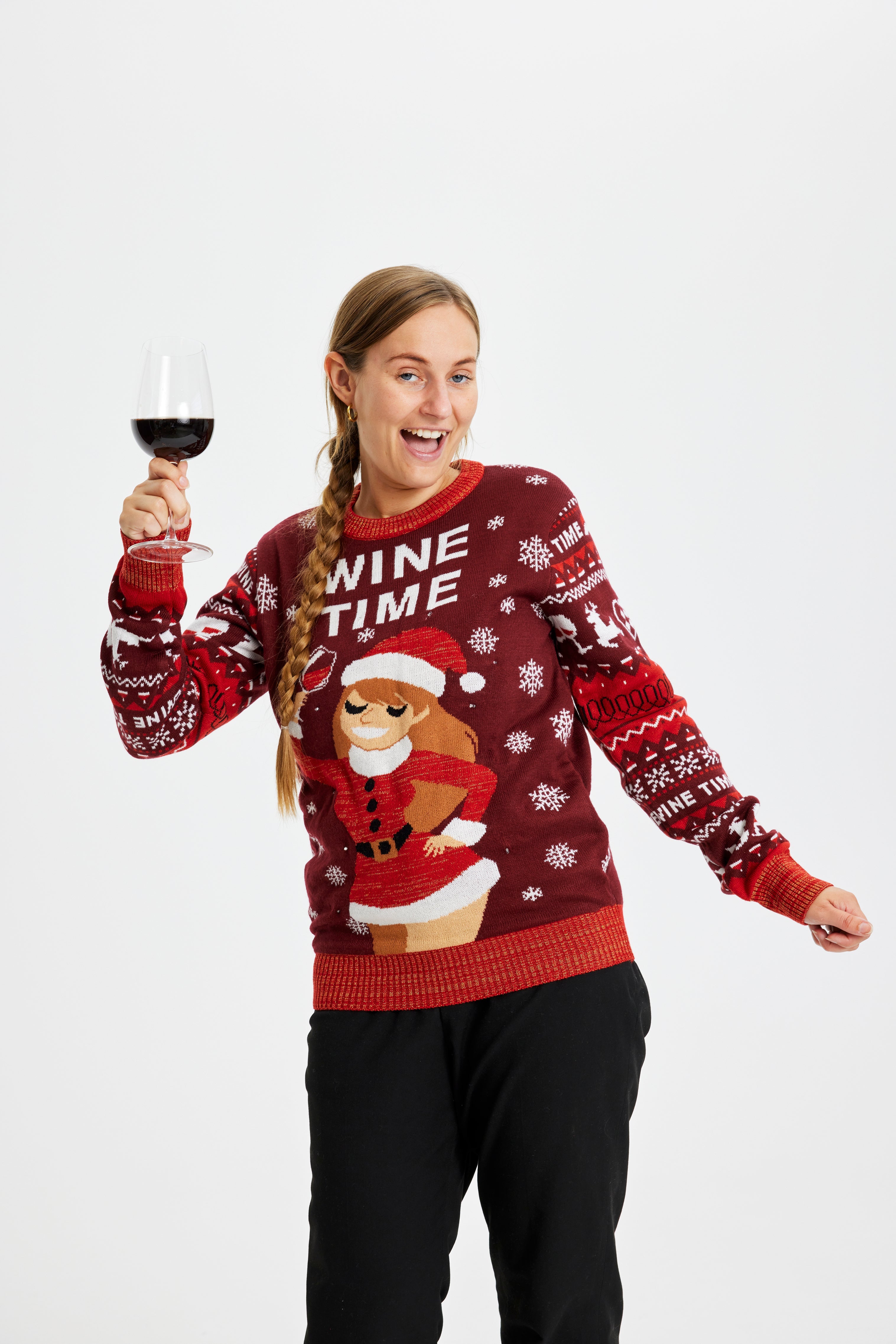 En smilende kvinde med et glad vin i en rød julesweater.
