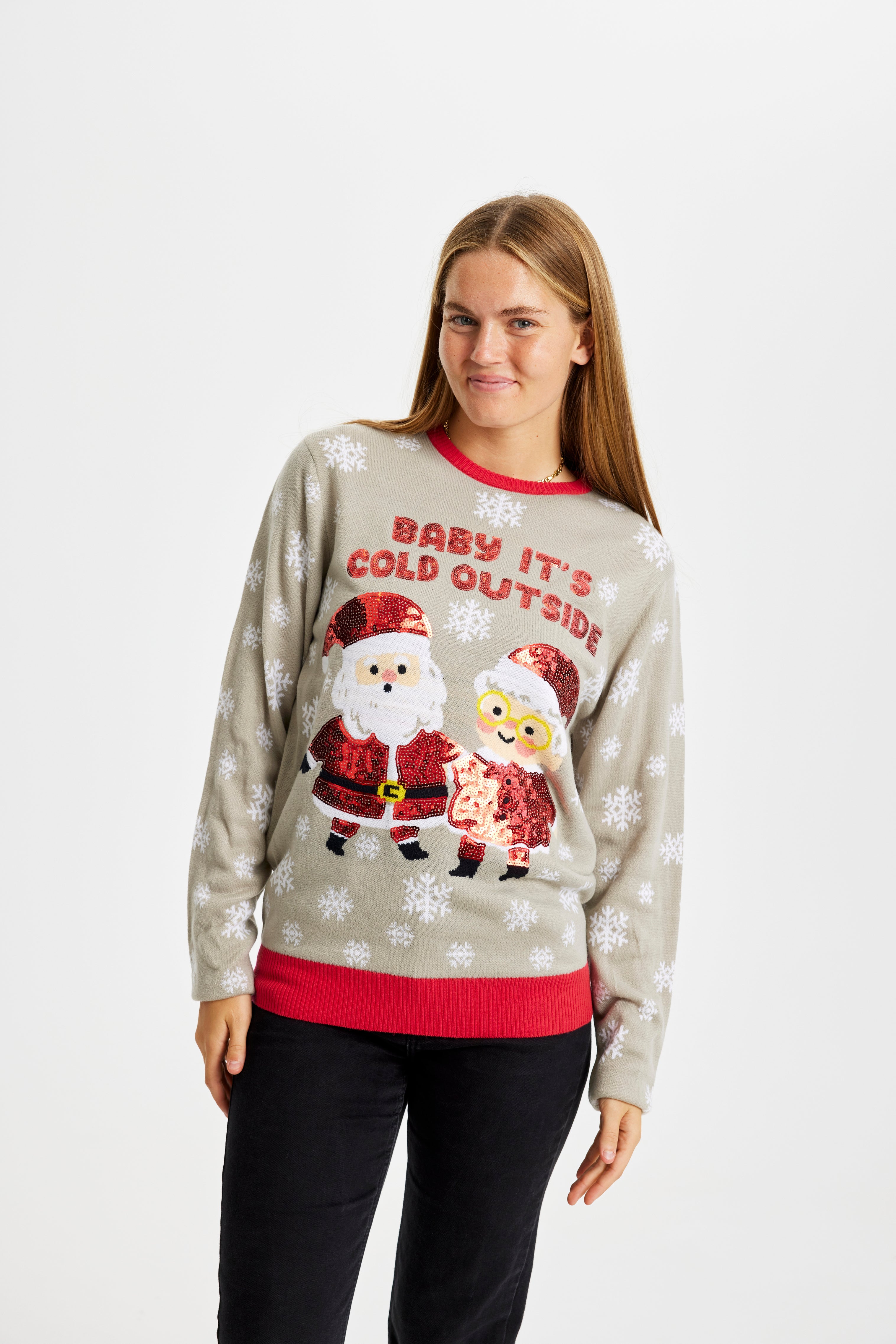En glad dame med en grå julesweater, hvor der ses snefnug og et nissepar under citatet 