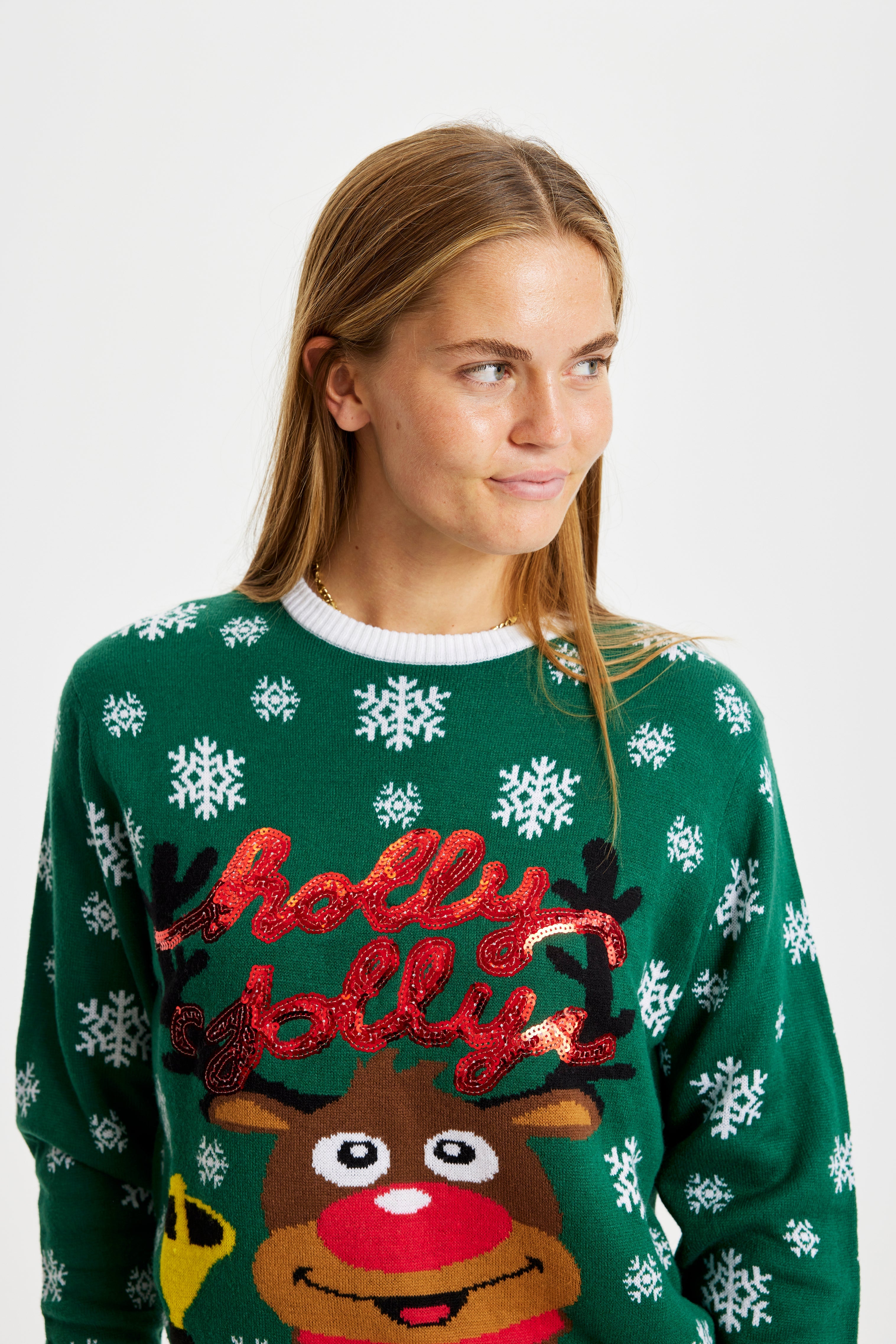 En smilende kvinder, der kigger til siden, iført en grøn julesweater.