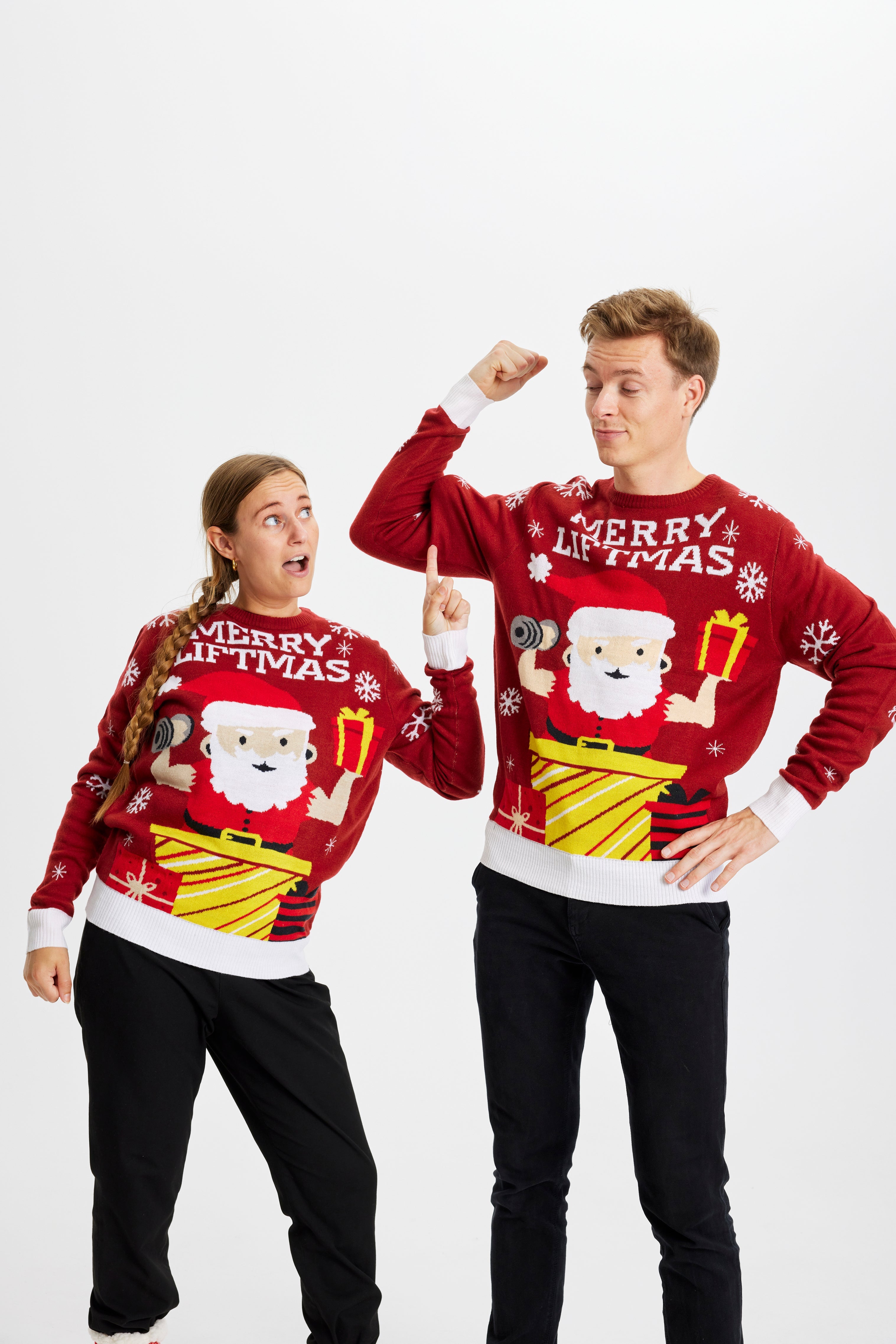 En dame og en mand poserer sammen i en rød julesweater.