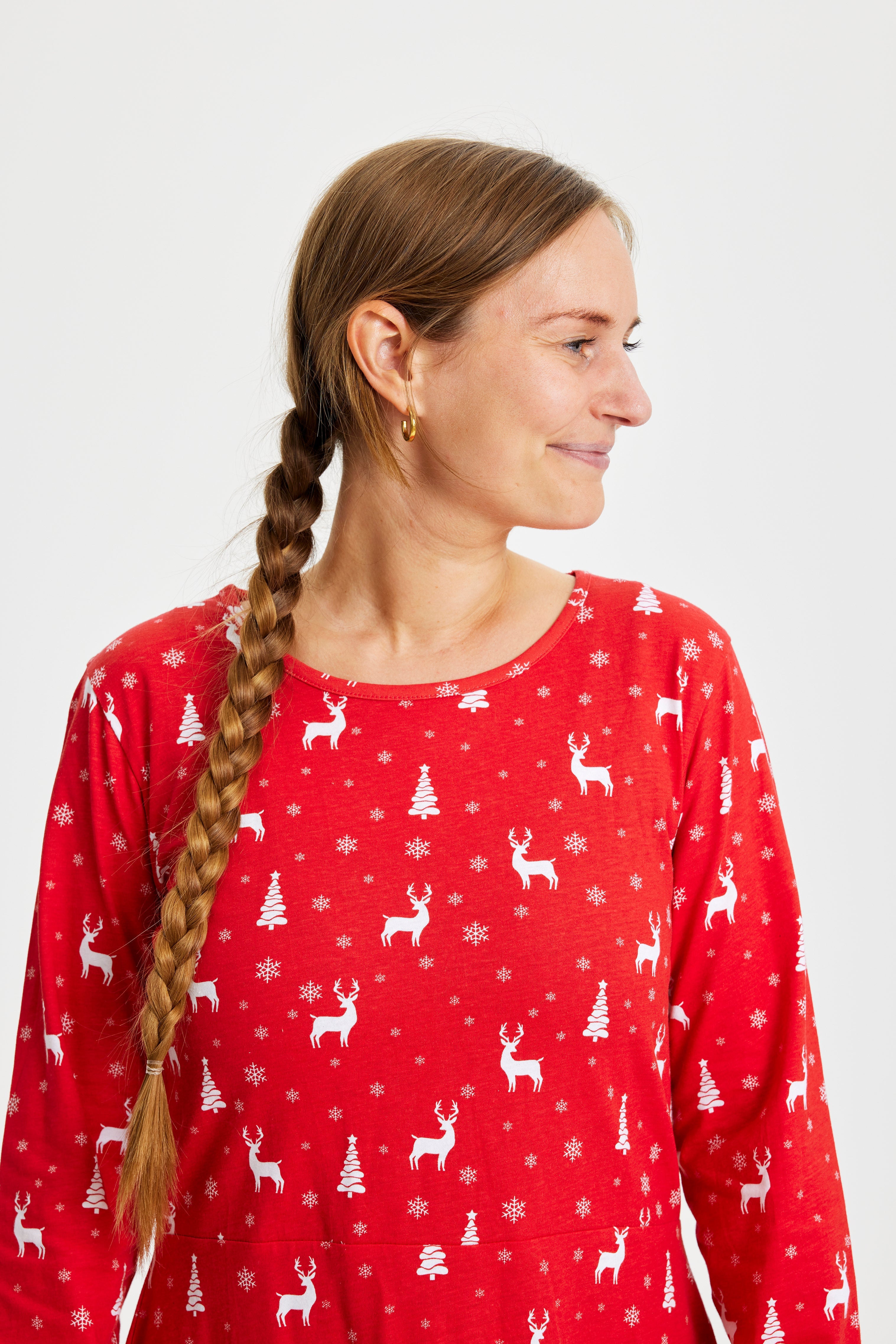 En kvinde kigger til siden og er iført en rød julekjole.