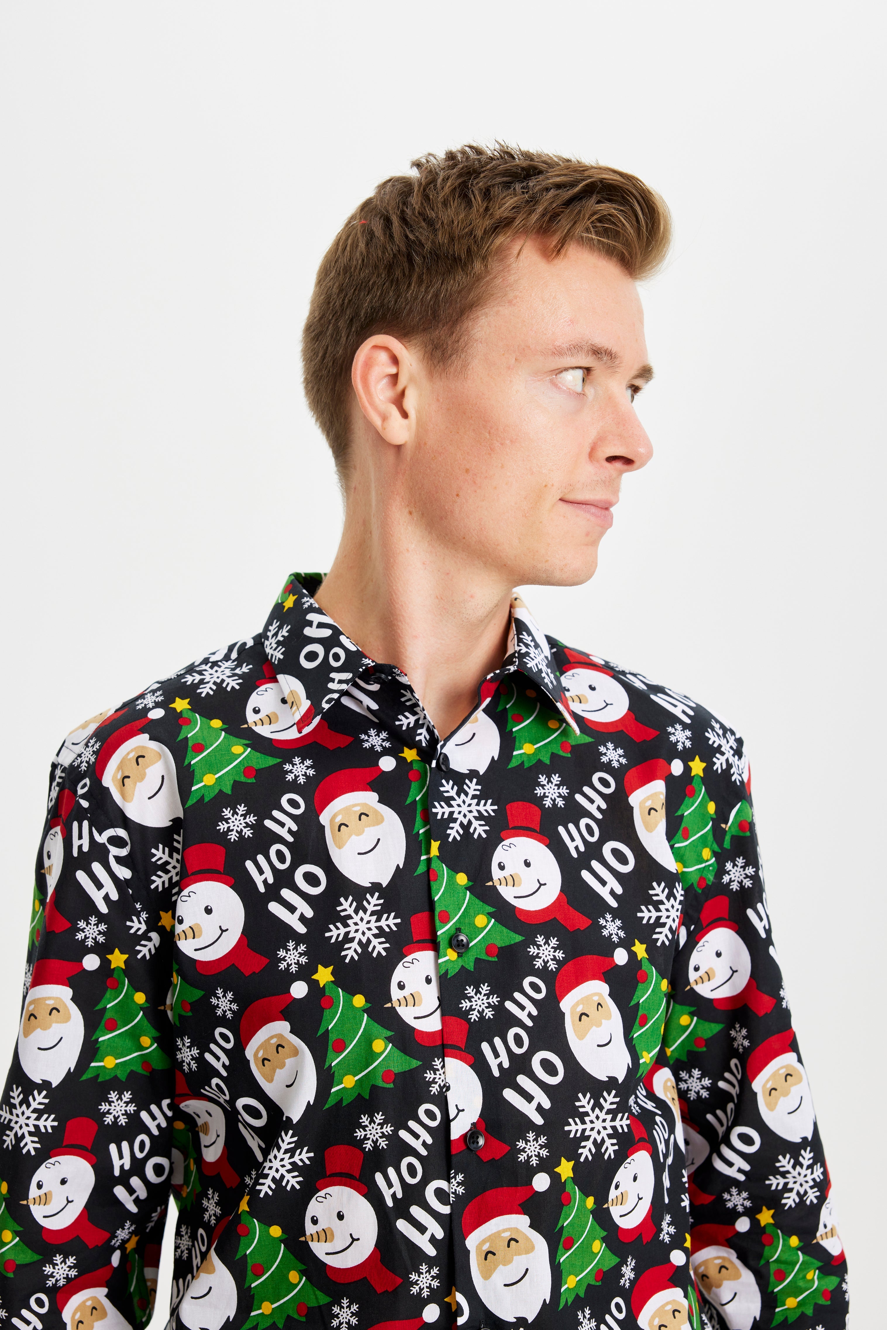 En mand kigger til siden og er iført en farverig juleskjorte.