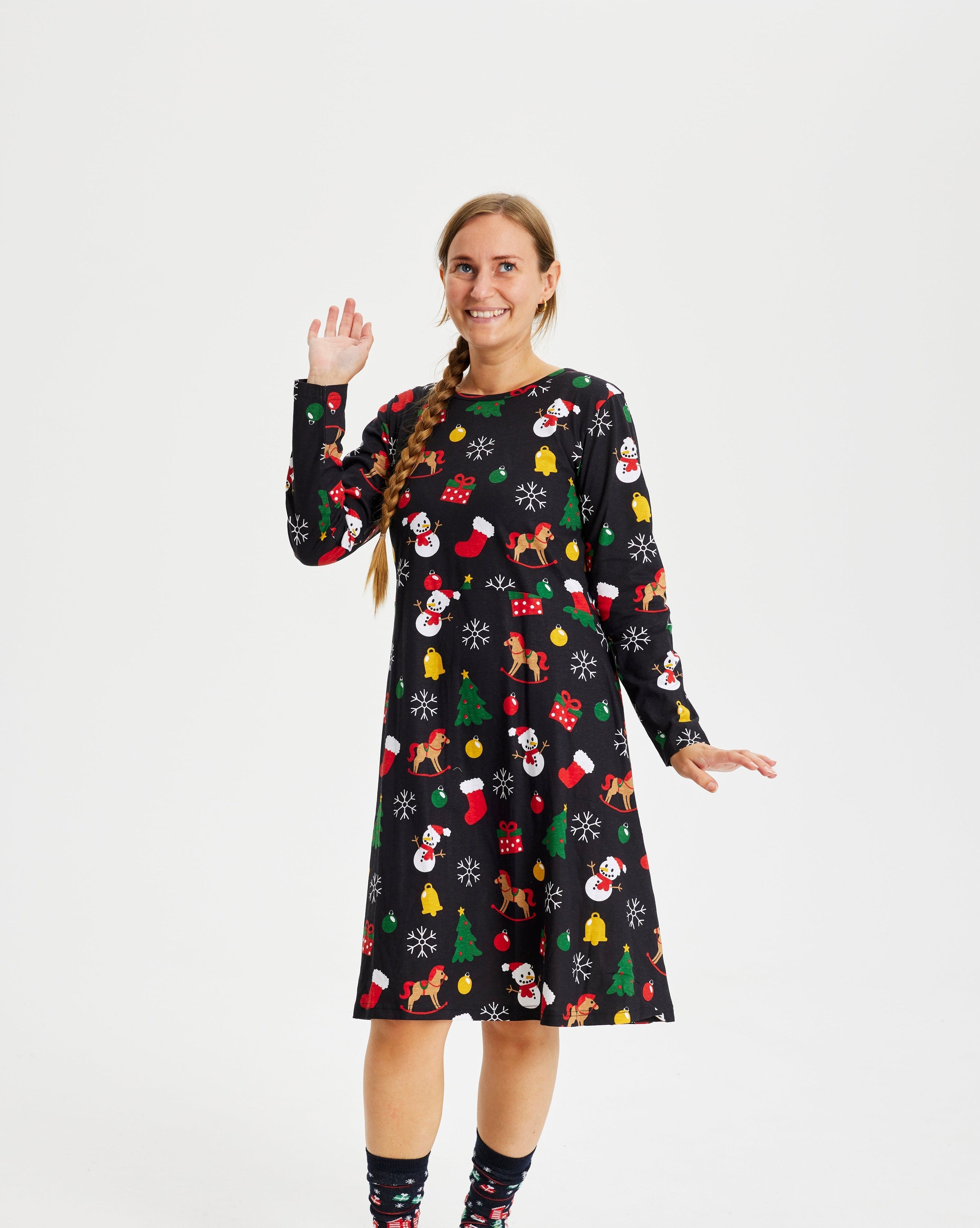 En smilende kvinde iført en sort julekjole med mønster.