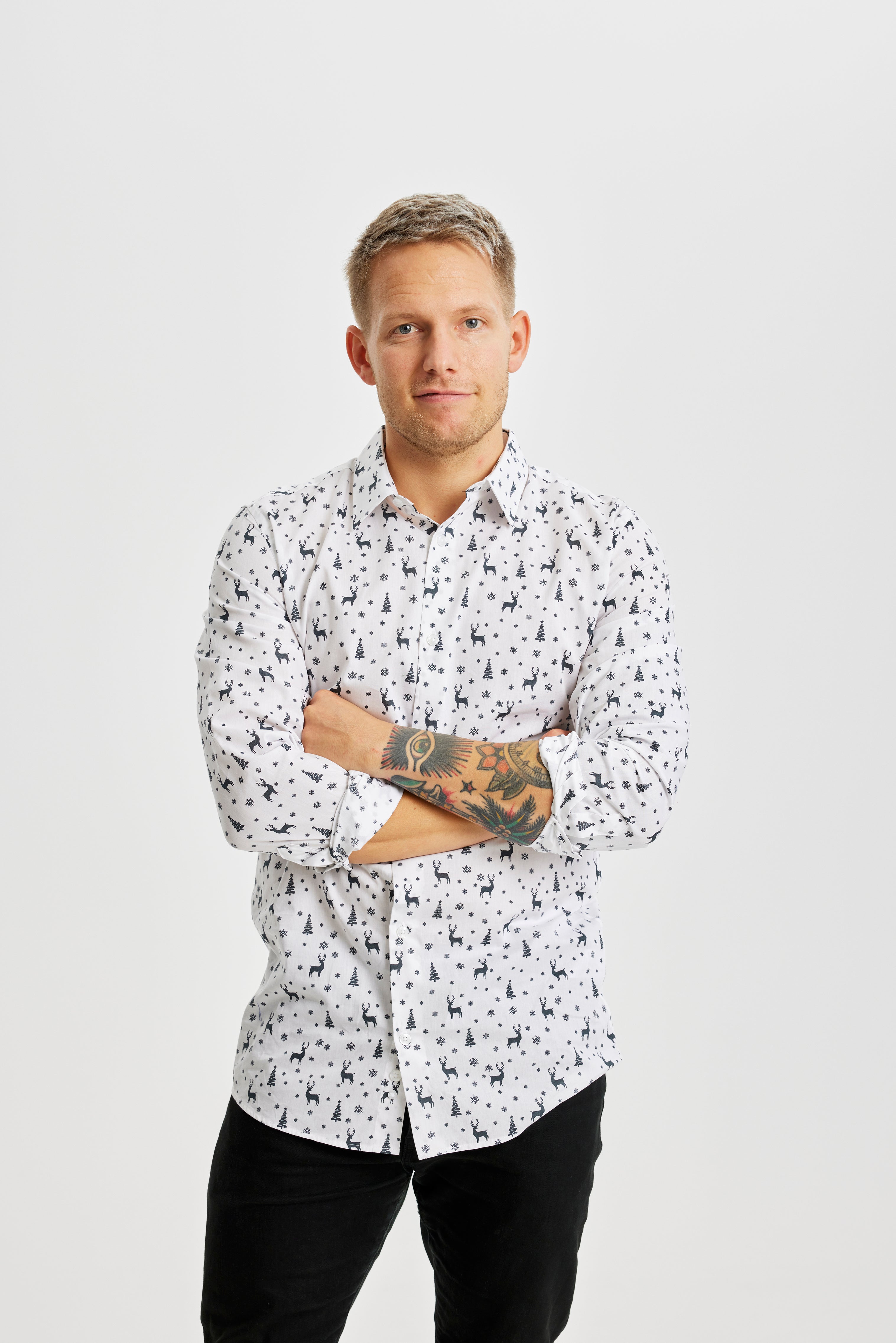 En mand iført en hvid juleskjorte med julemønster.