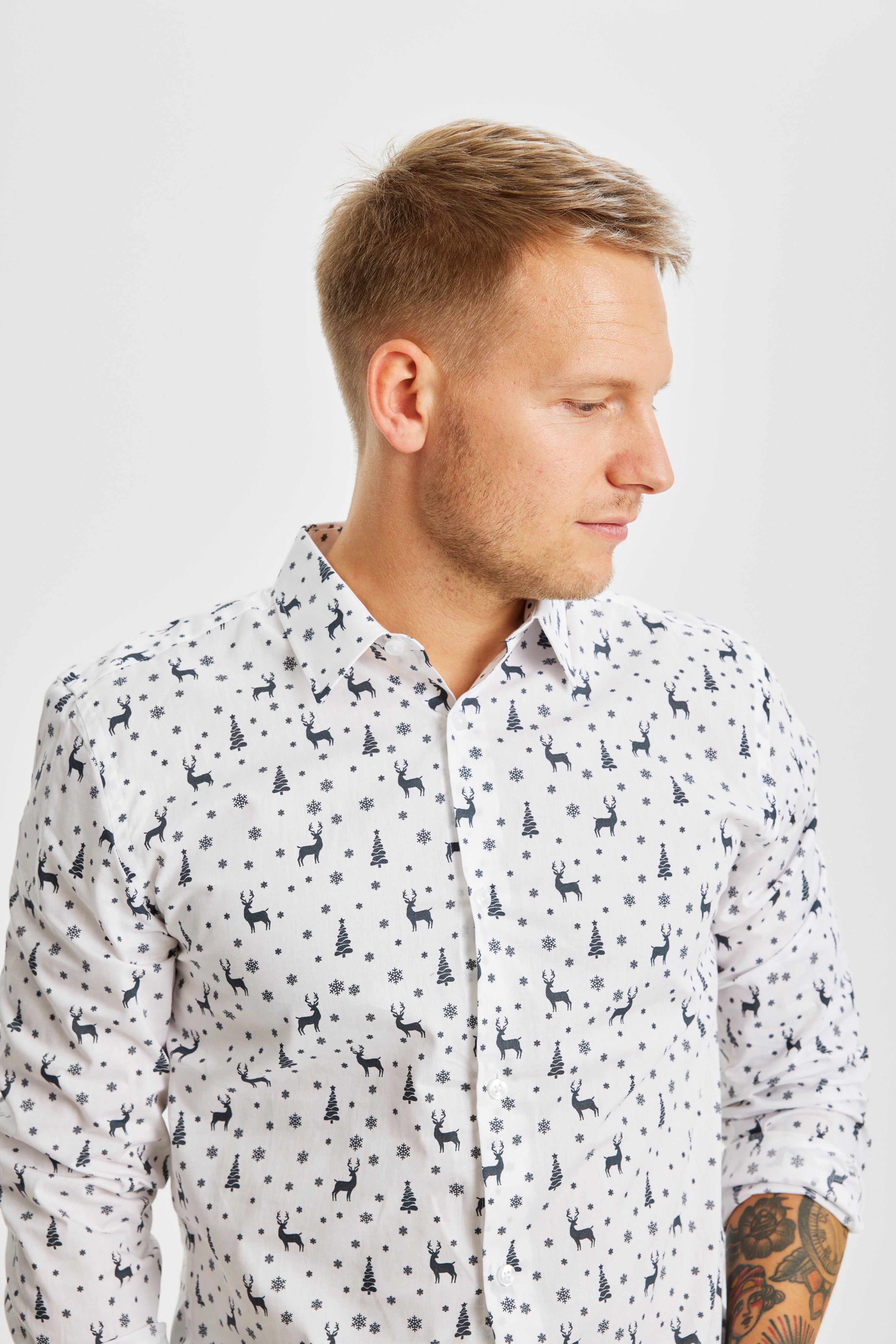 En mand kigger til siden og står i en hvis juleskjorte.