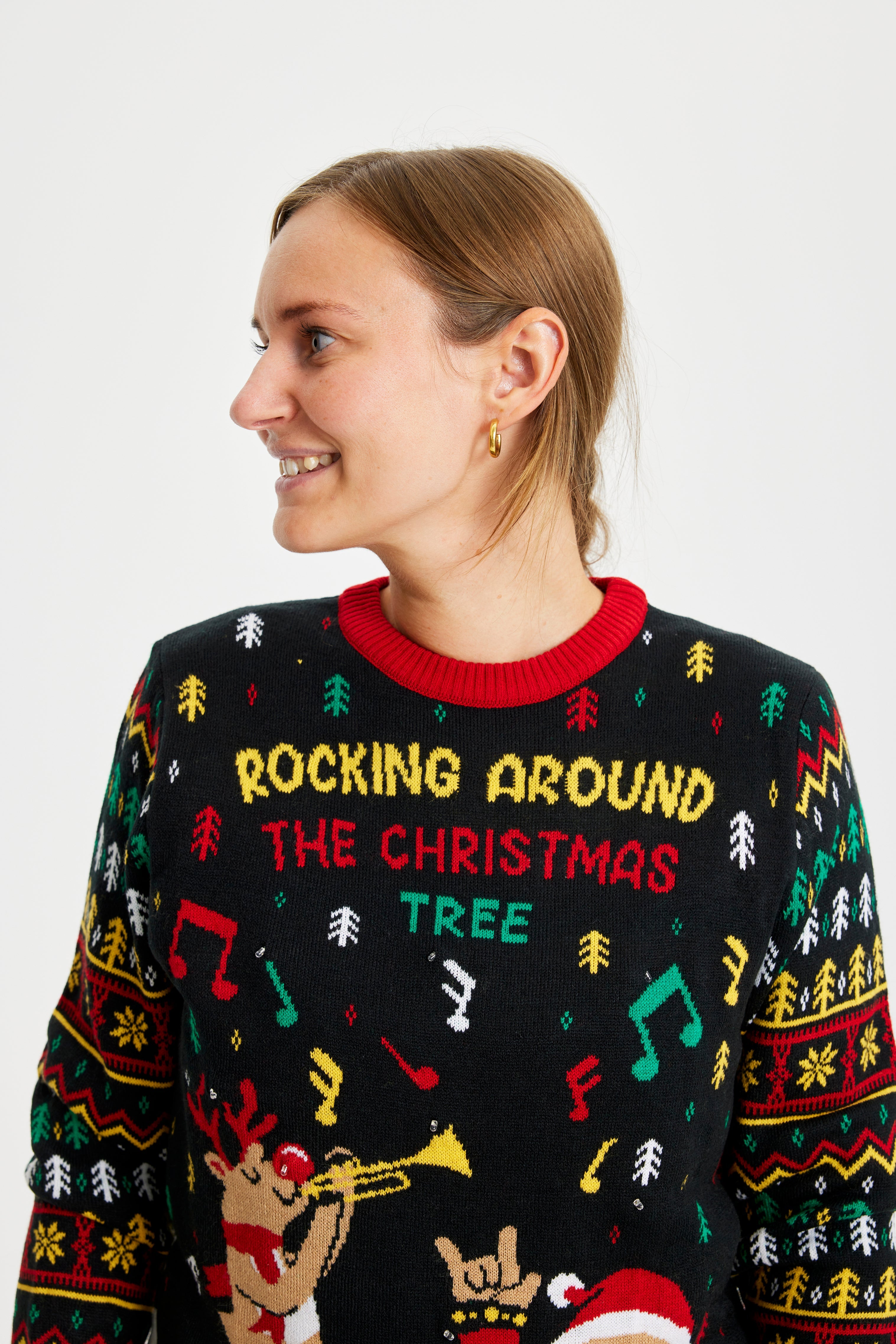 En dame der kigger til siden er iført en sort julesweater med juleprint på.