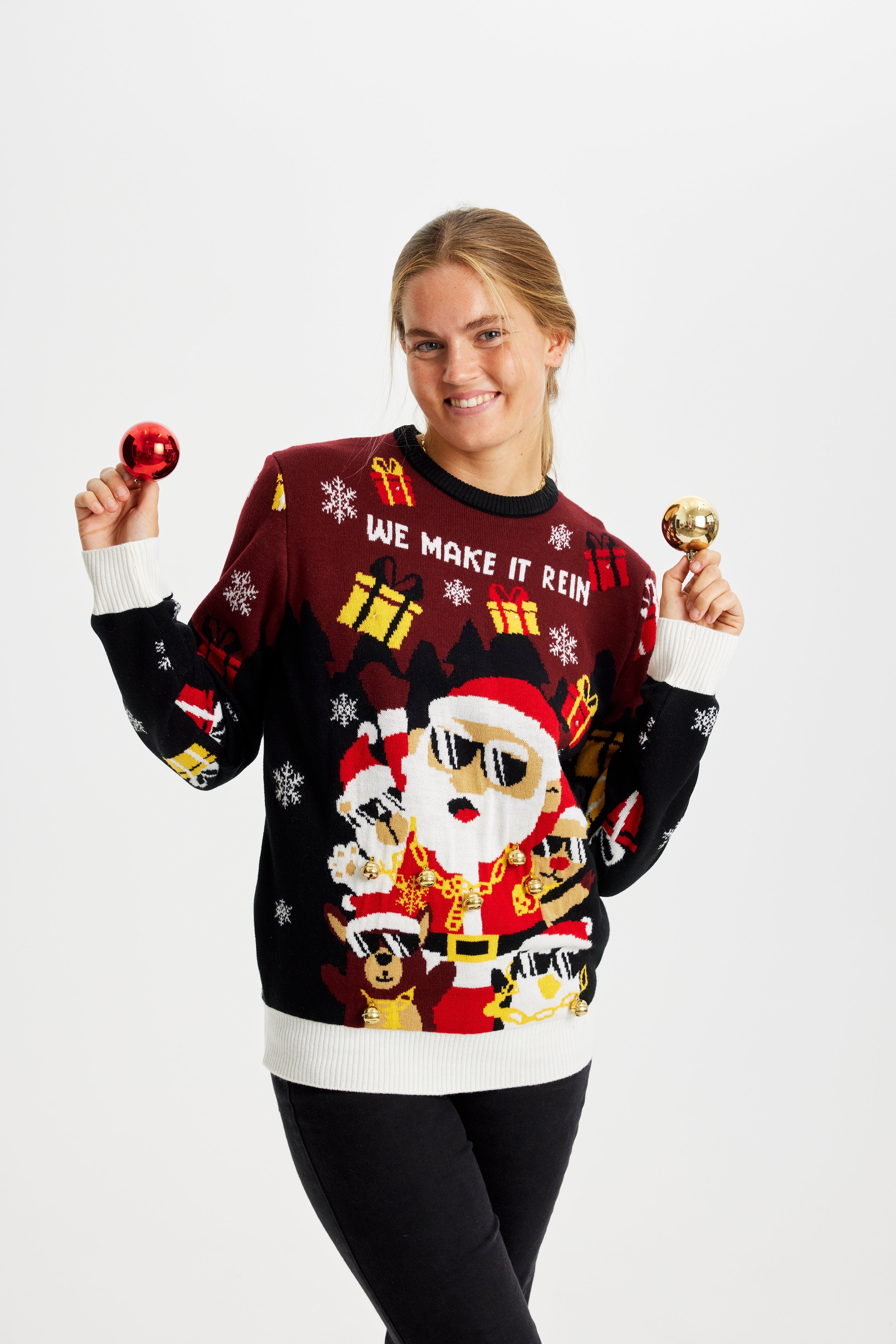 En smilende kvinde i en mørkerød julesweater med julemænd og gaver på.